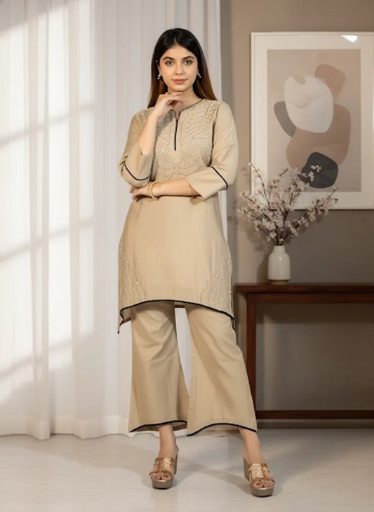 Woman wearing a beige kurta with palazzo pants in a well-lit room.