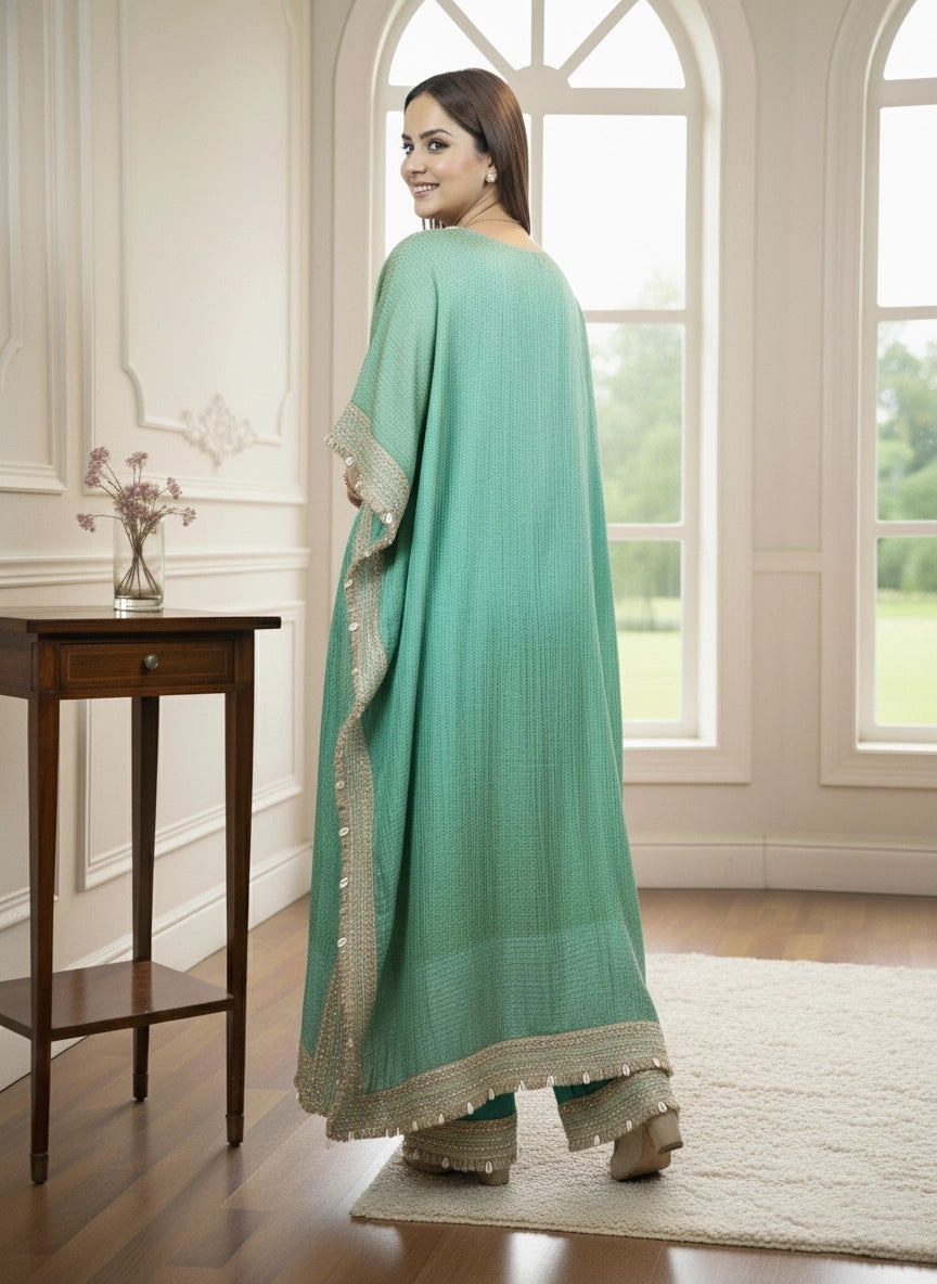 Woman in a teal traditional outfit standing in a room with a wooden table and window.