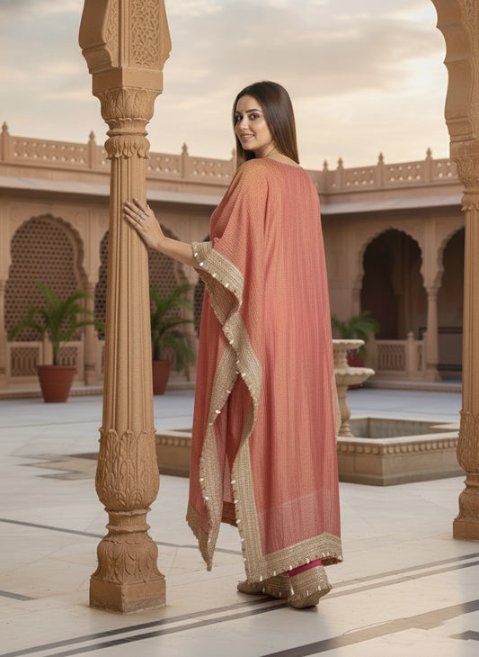 Woman in a pink saree with gold border standing in an architectural setting
