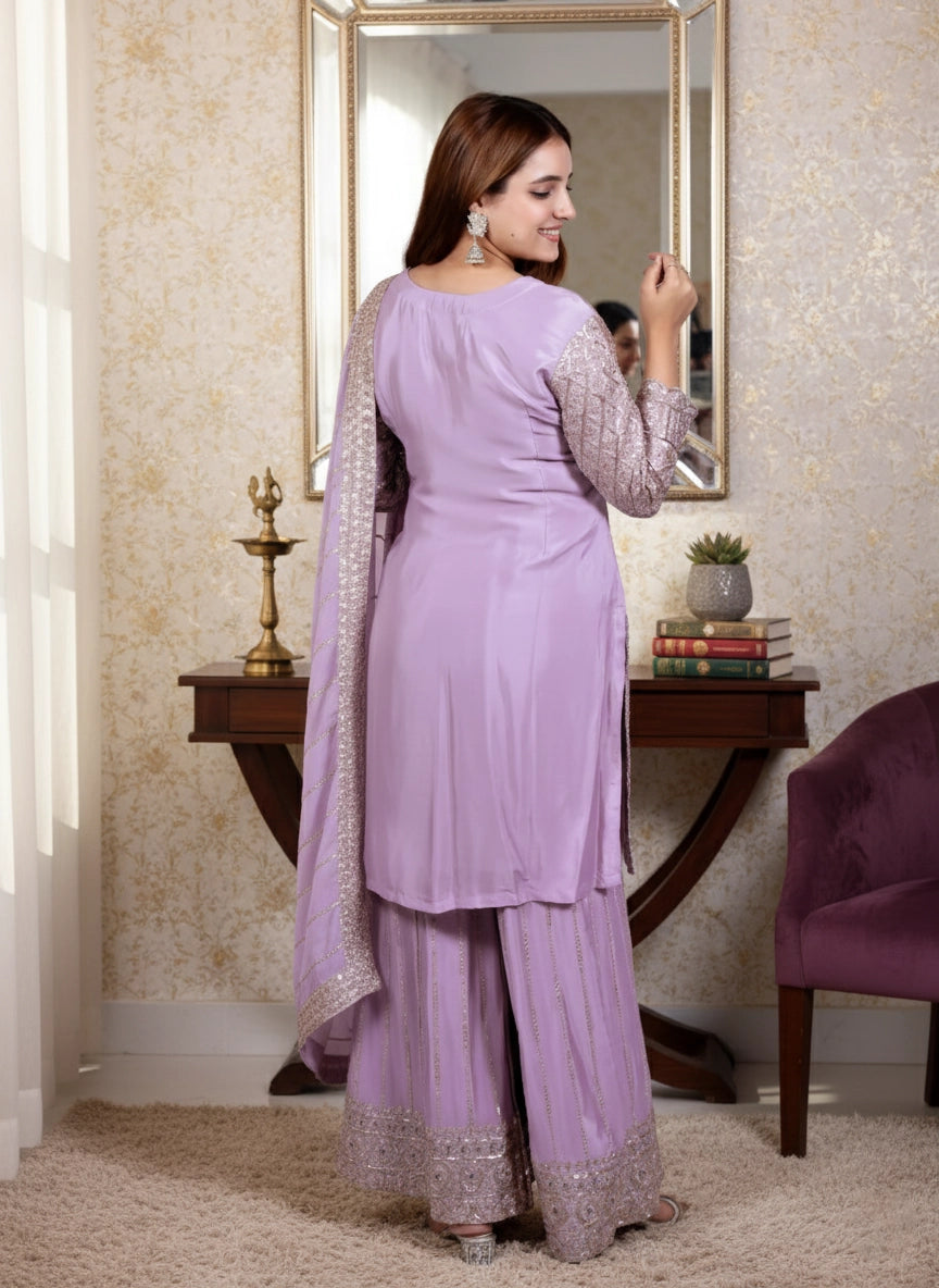 Woman in a lavender traditional outfit standing in a room with a mirror and decor.