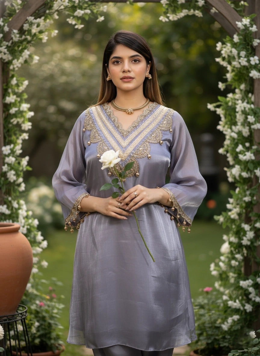 Woman in a light blue embroidered dress holding a white flower in a garden setting