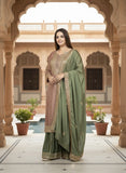 Woman in a green saree standing in an ornate architectural setting with a pool in the background.