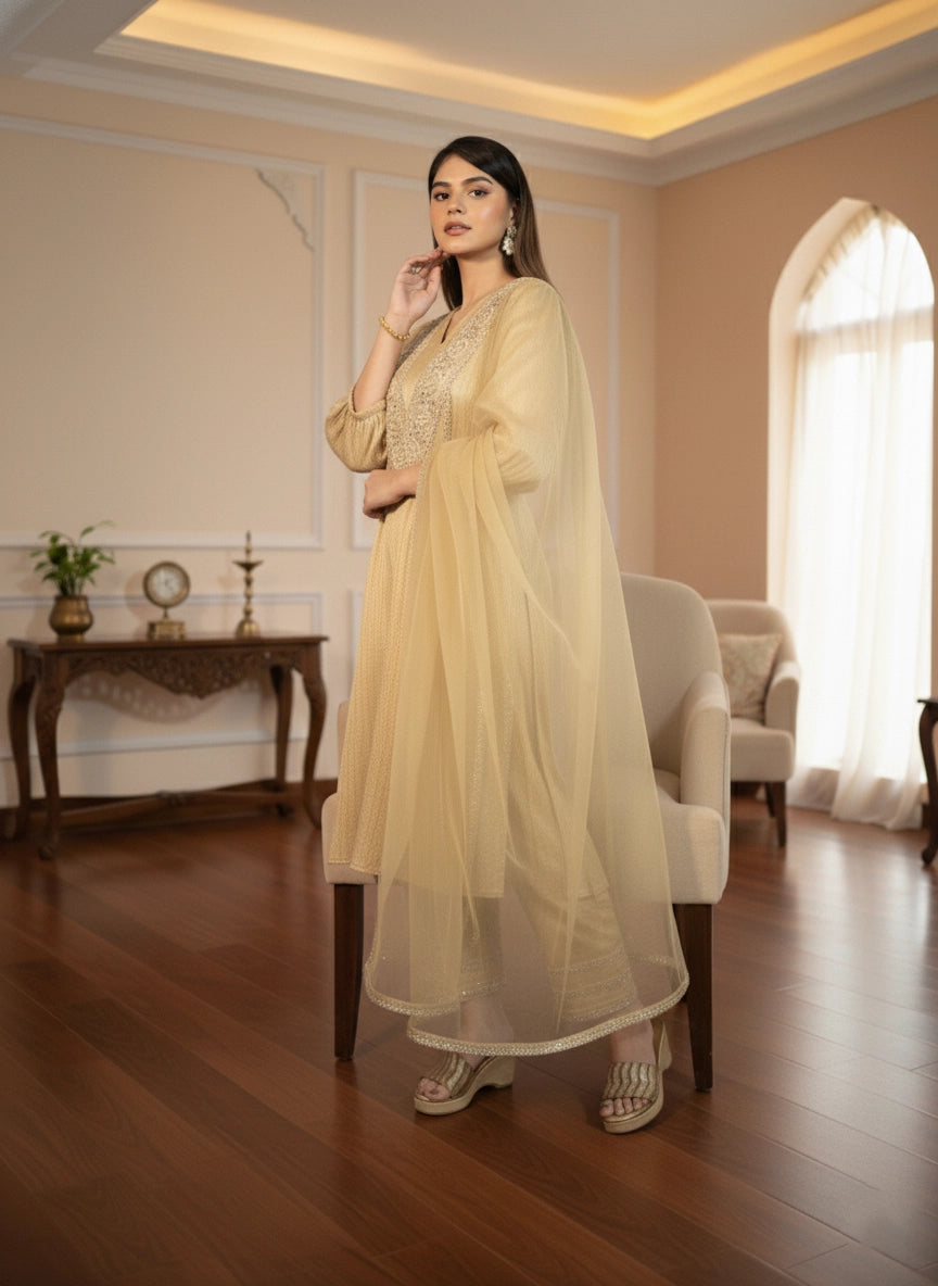 Woman in a beige traditional outfit standing in a well-lit room with wooden flooring and decorative elements.