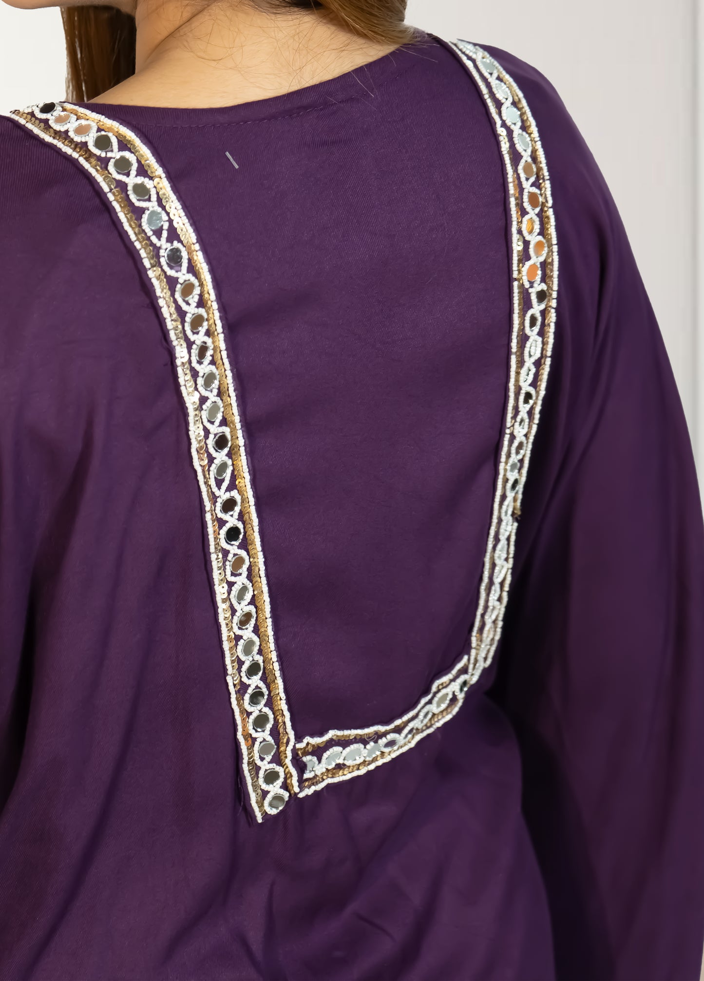 Purple garment with intricate white embroidery on a plain background