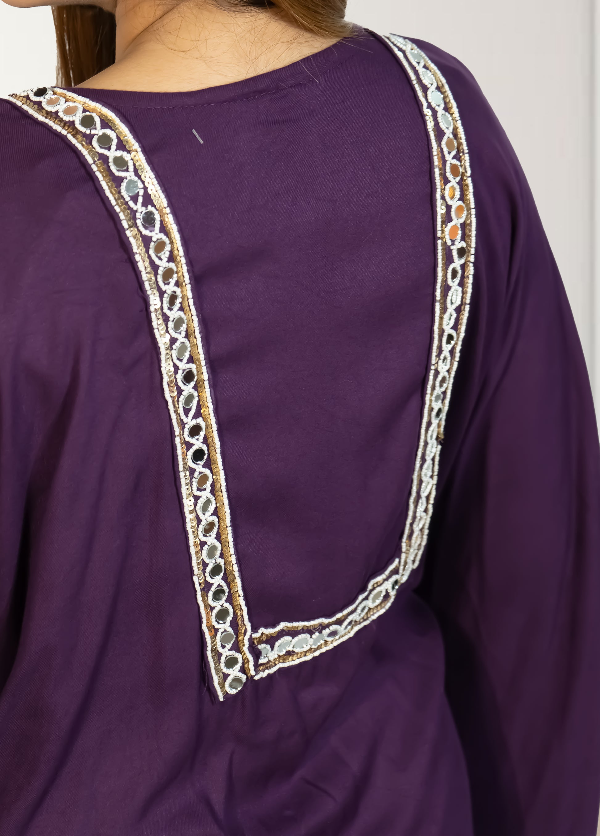 Purple garment with intricate white embroidery on a plain background