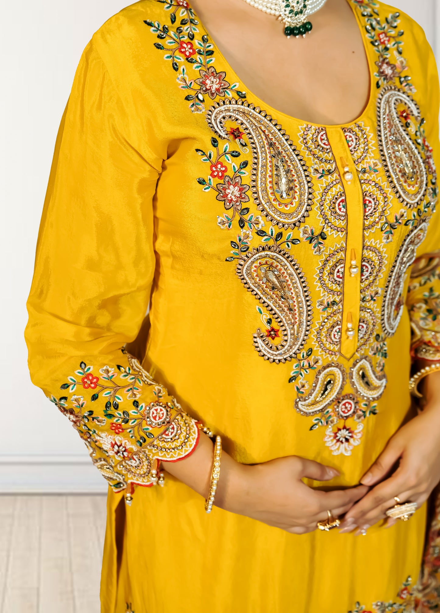 Yellow embroidered traditional outfit with intricate patterns on a plain background
