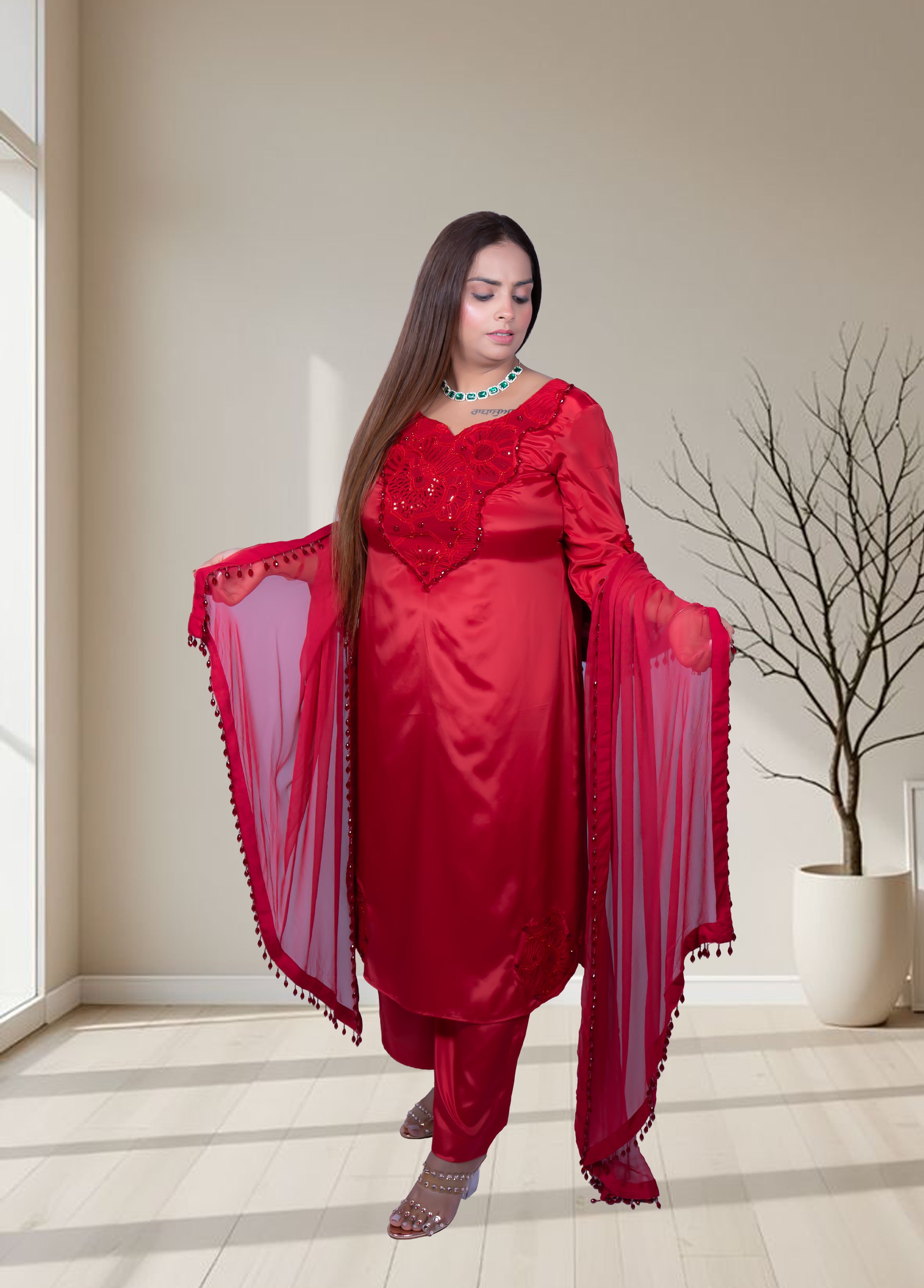 Woman wearing a red traditional outfit with a matching dupatta in a well-lit room.