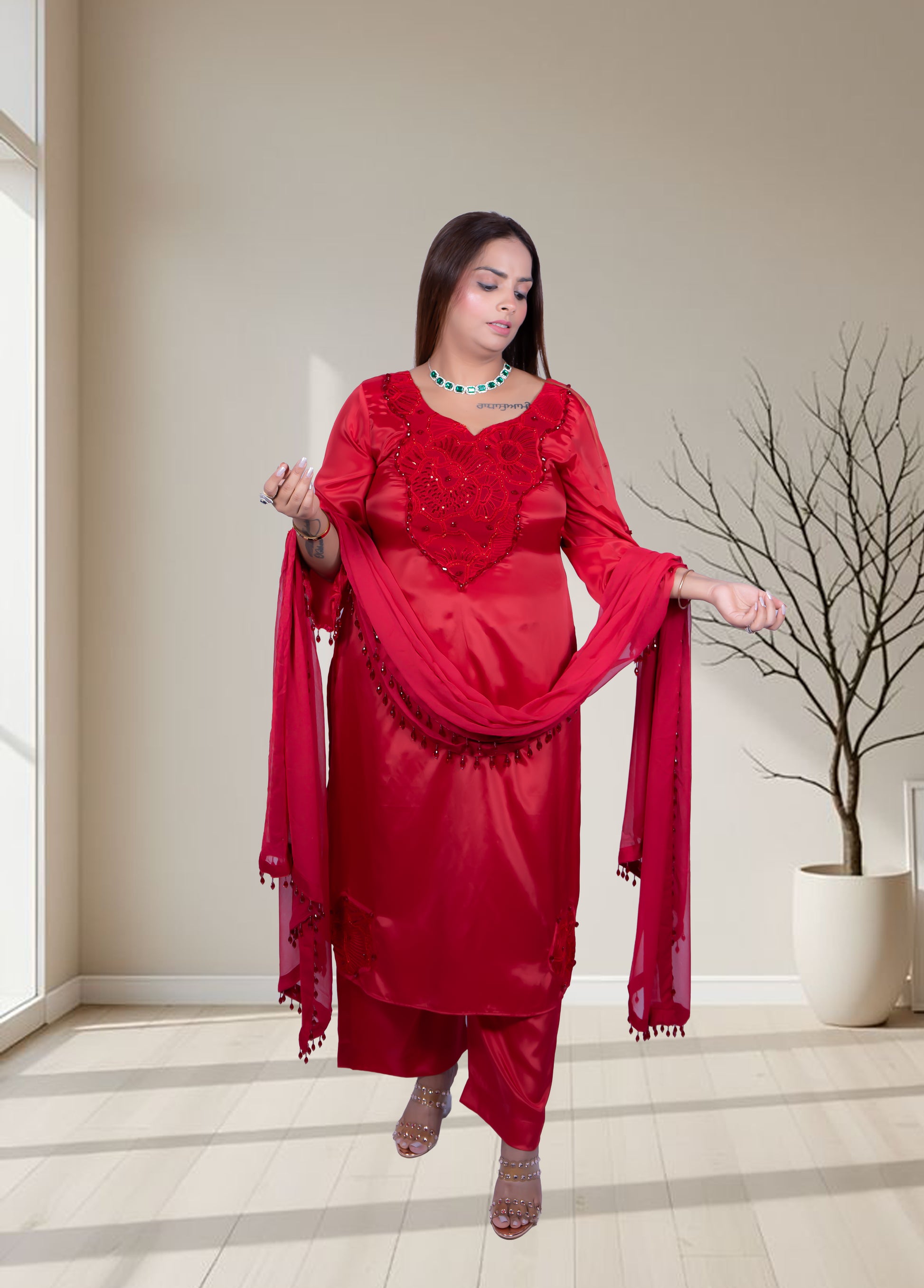 Woman in a red traditional outfit standing in a room with a neutral color scheme.