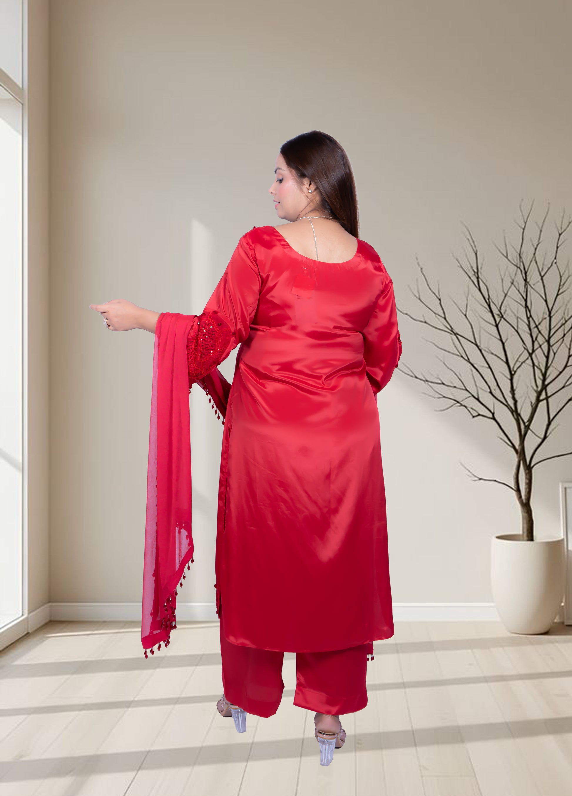 Woman in a red traditional outfit standing in a room with a neutral background