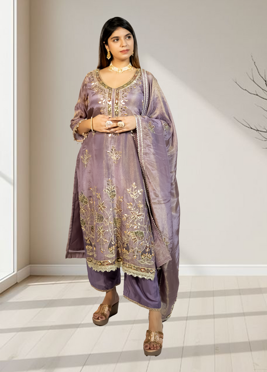 Woman wearing a traditional outfit with intricate designs in a neutral setting