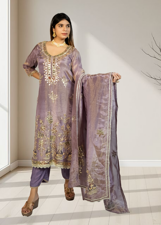 Woman wearing a traditional embroidered outfit with a matching dupatta in a well-lit room.