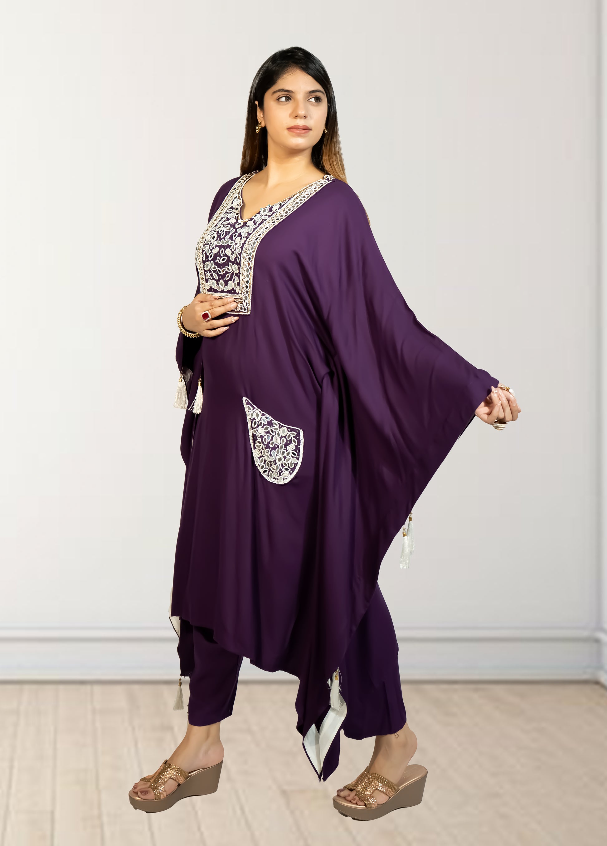 Woman wearing a purple outfit with white embroidery against a white background