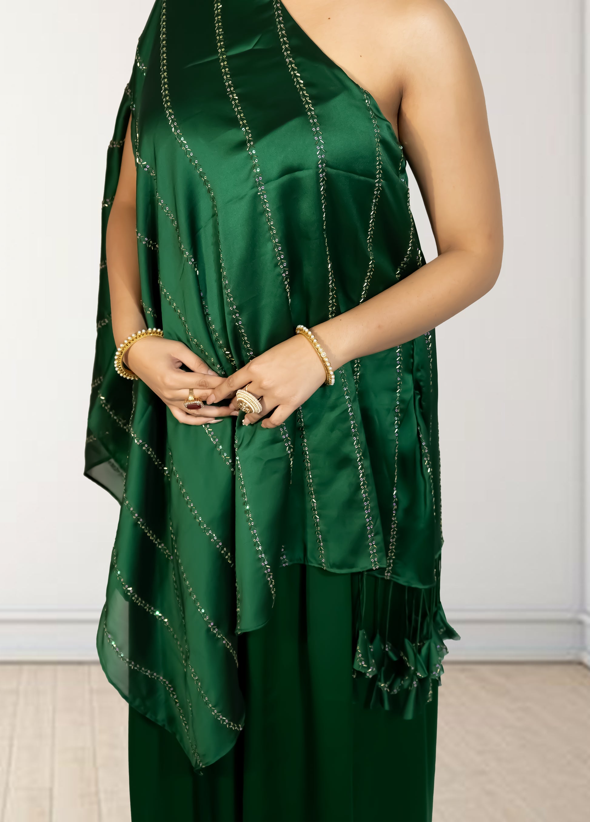 Green one-shoulder dress with ruffled details on a plain background