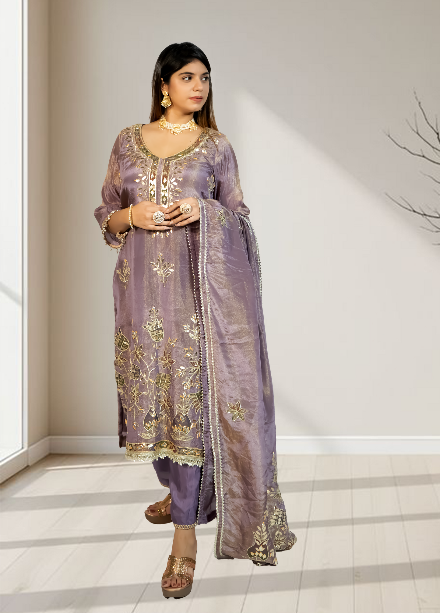Woman wearing a traditional embroidered outfit in a minimalistic room.