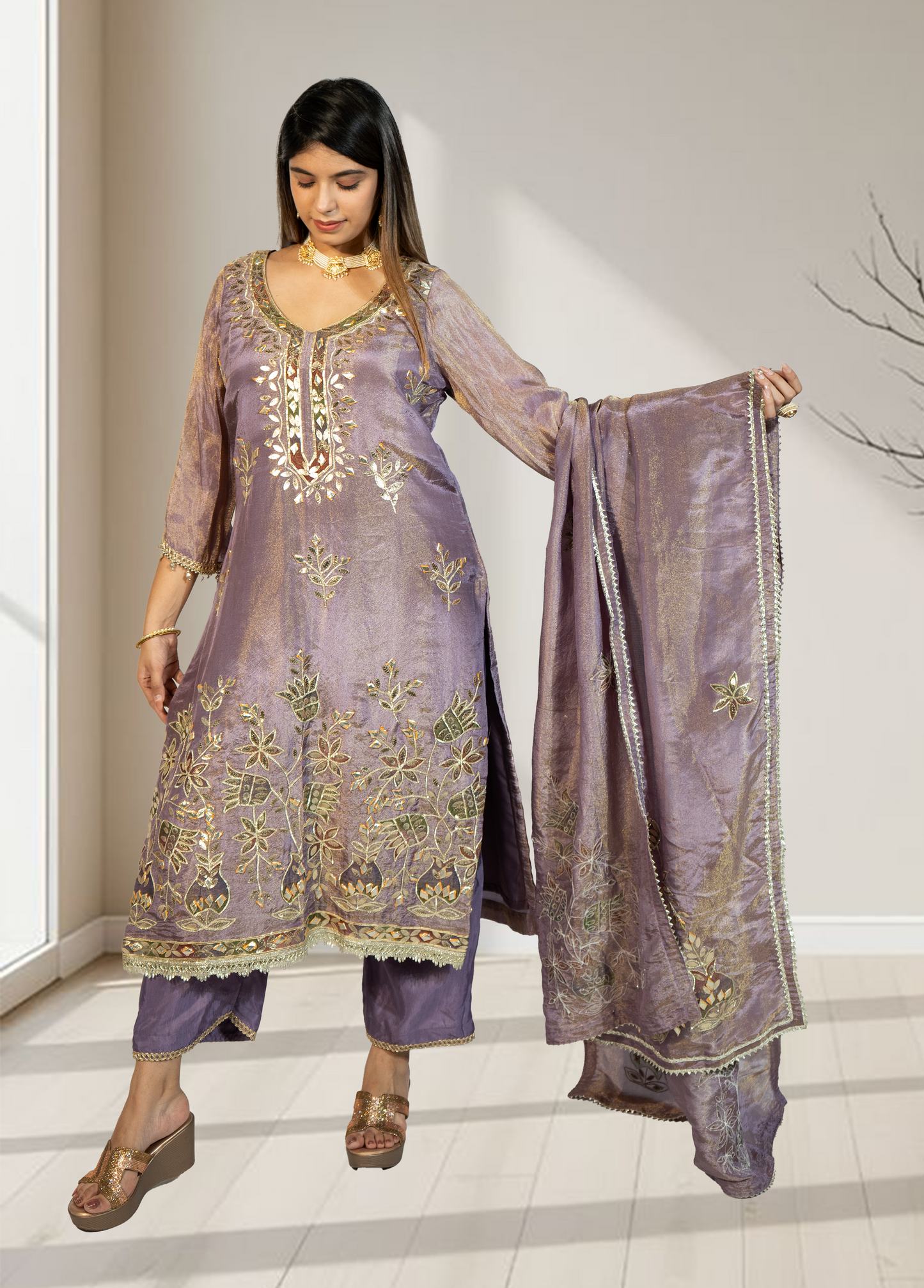 Woman wearing a purple embroidered outfit with a matching dupatta, standing indoors.