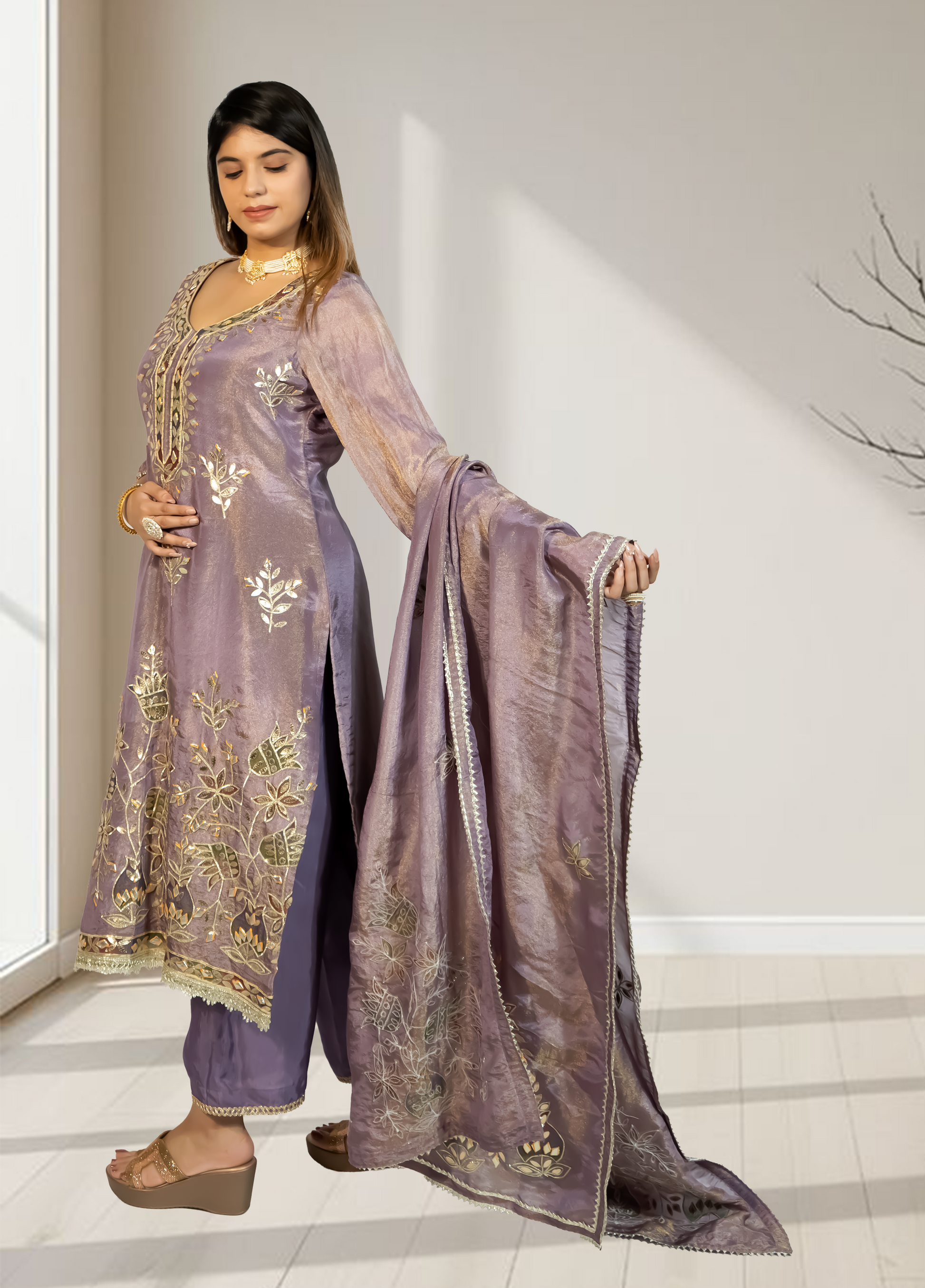 Woman wearing a traditional outfit with a purple dupatta in a well-lit room.