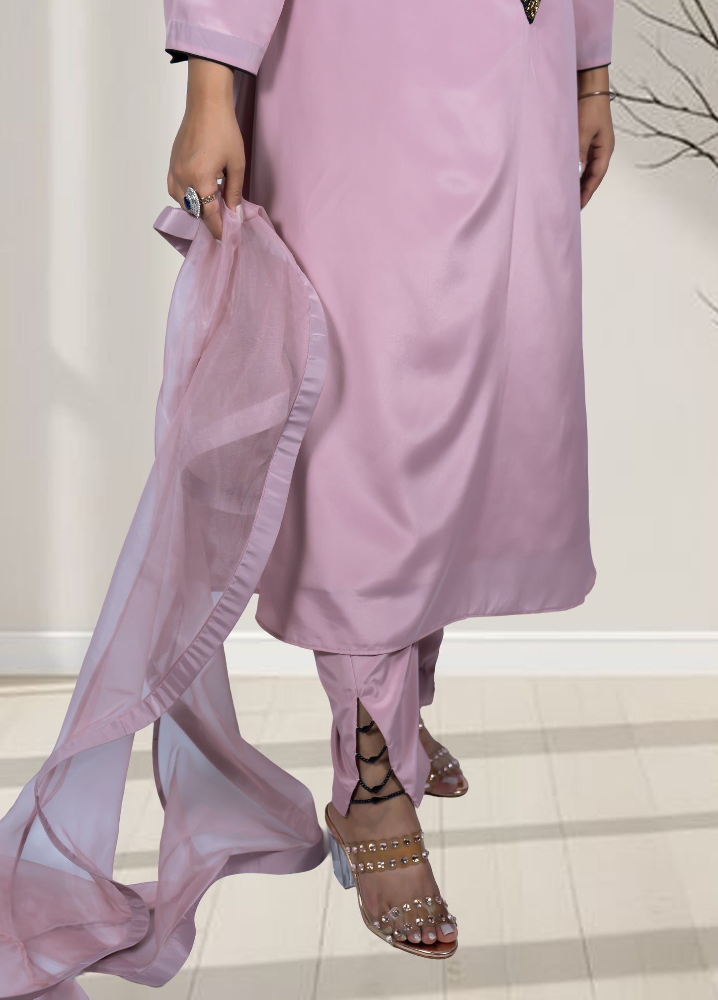 Person wearing a light pink traditional outfit with a sheer dupatta, standing on a white floor.