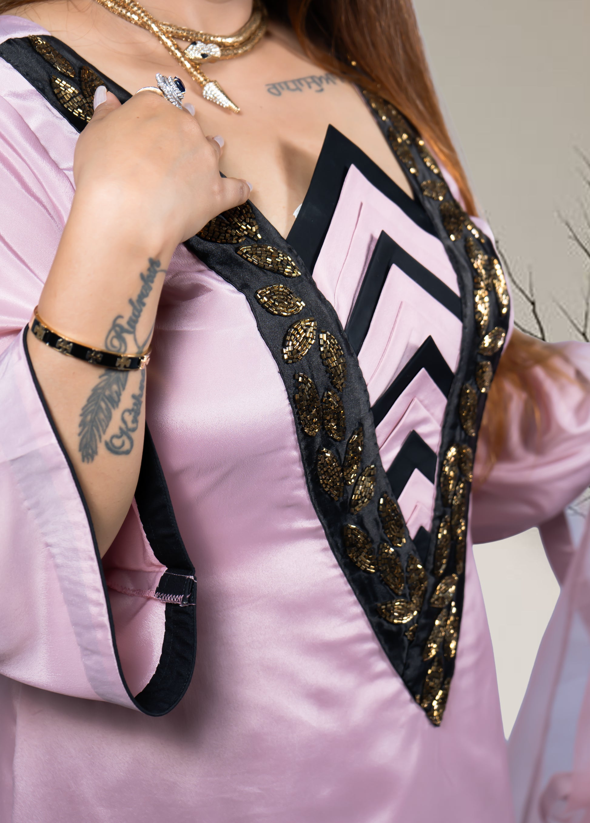 Person wearing a pink garment with black and gold decorative elements.