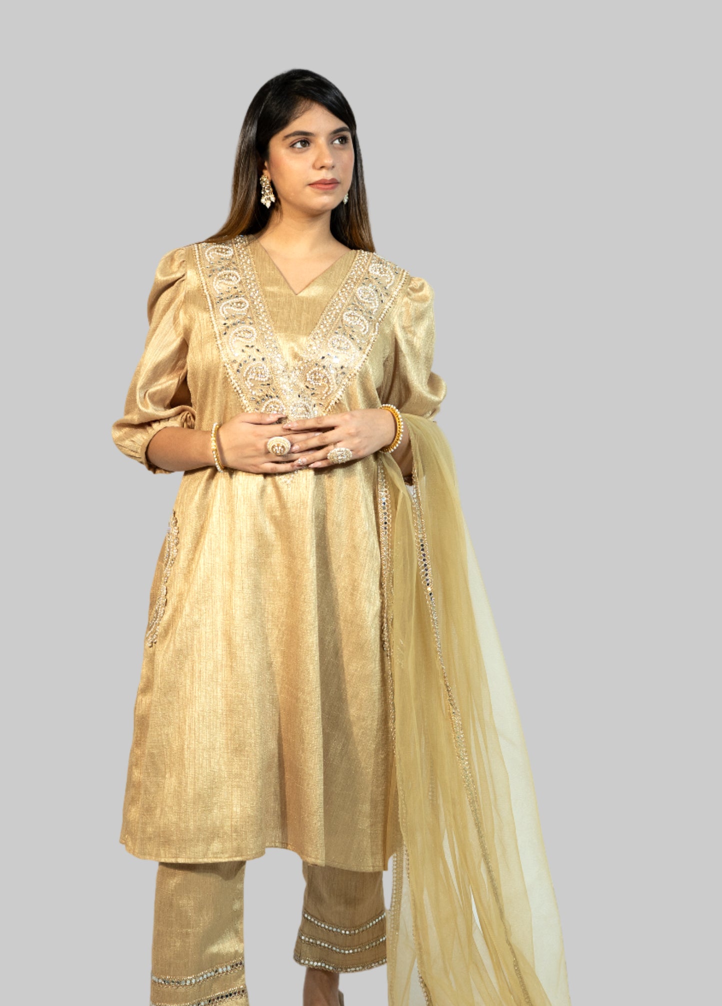 Woman wearing a gold traditional outfit with a plain background