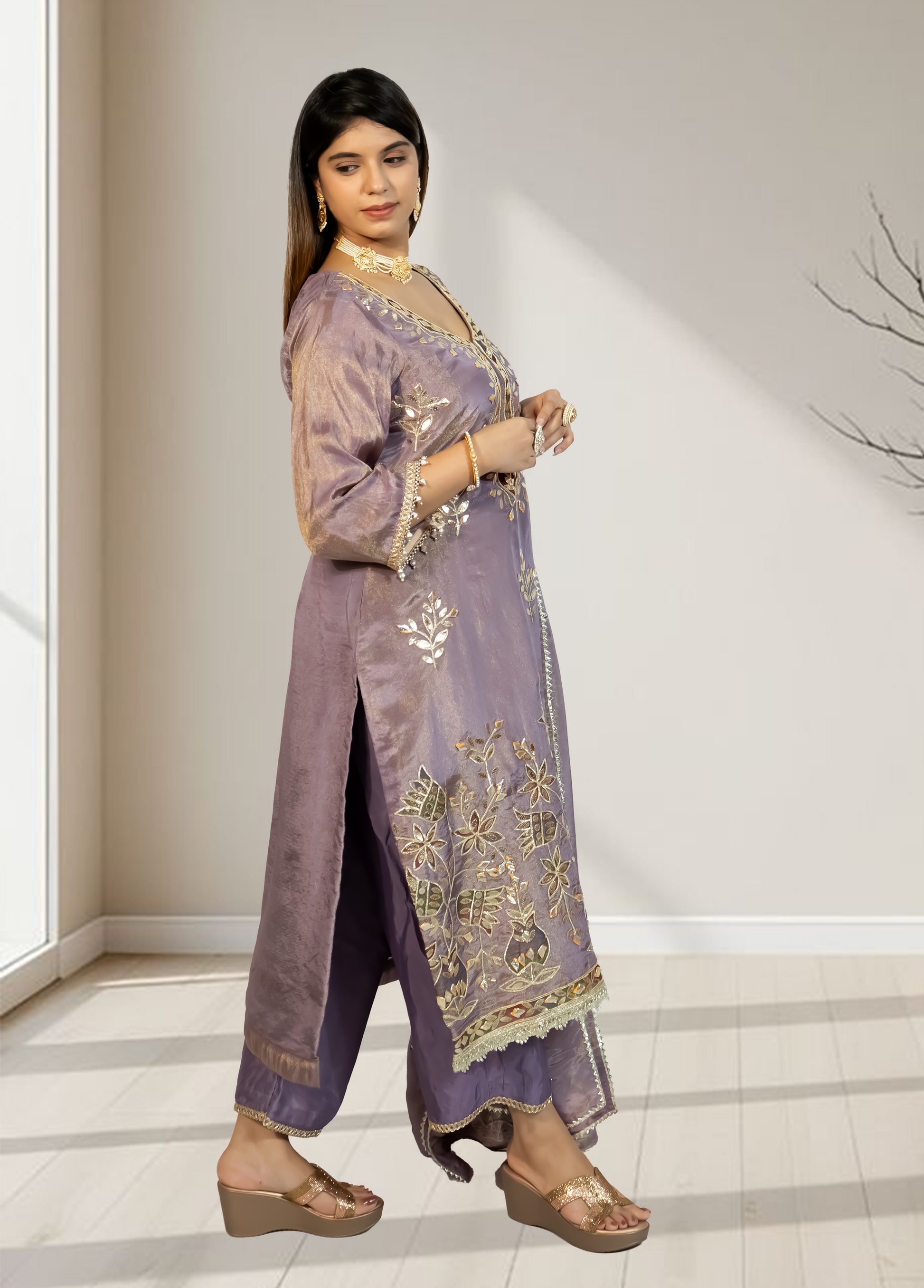 Woman wearing a traditional outfit with intricate designs indoors.