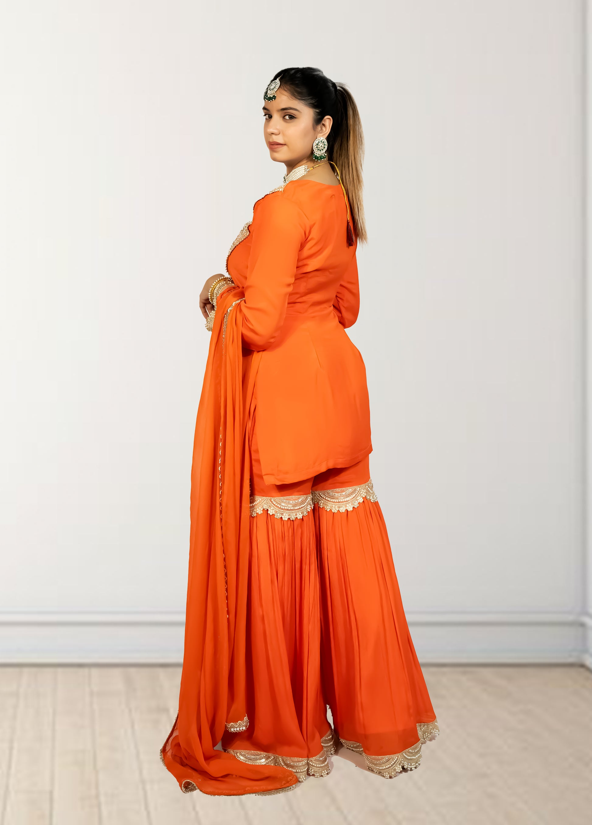 Woman wearing an orange traditional outfit with a white background