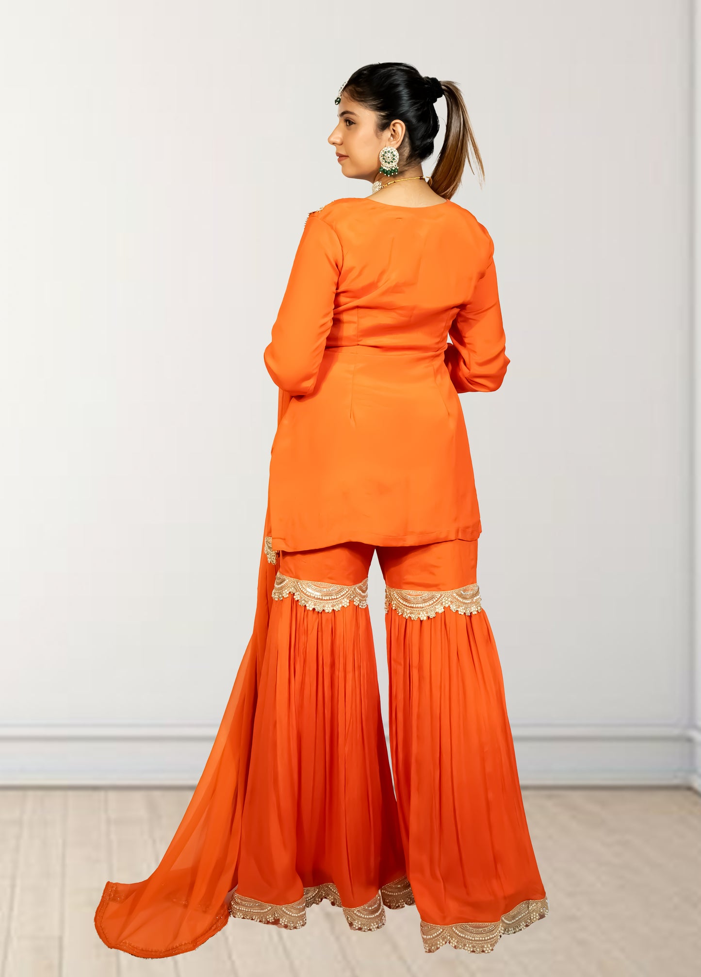 Woman wearing an orange traditional outfit with lace details on a white background