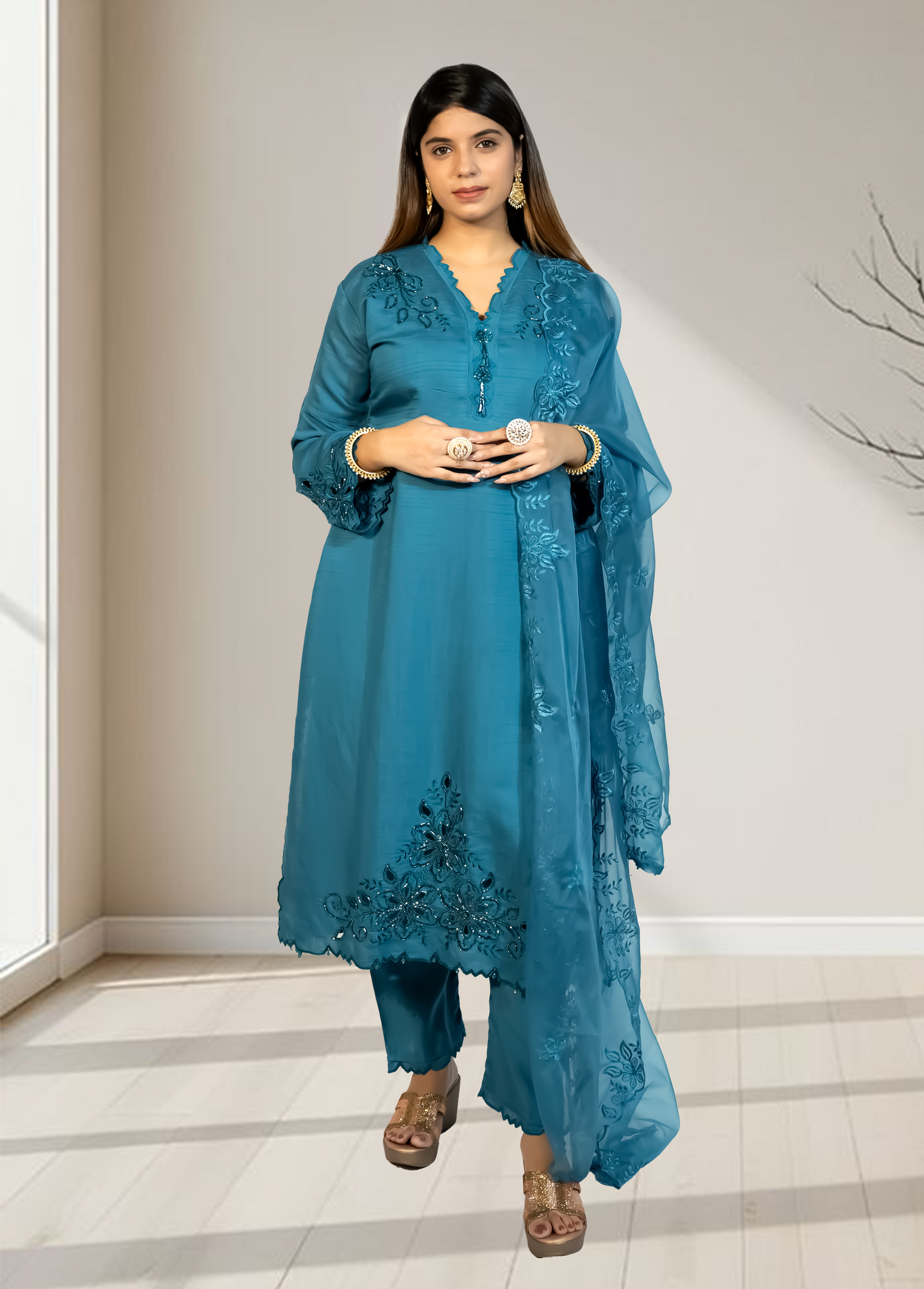 Woman wearing a blue embroidered outfit in a minimal indoor setting