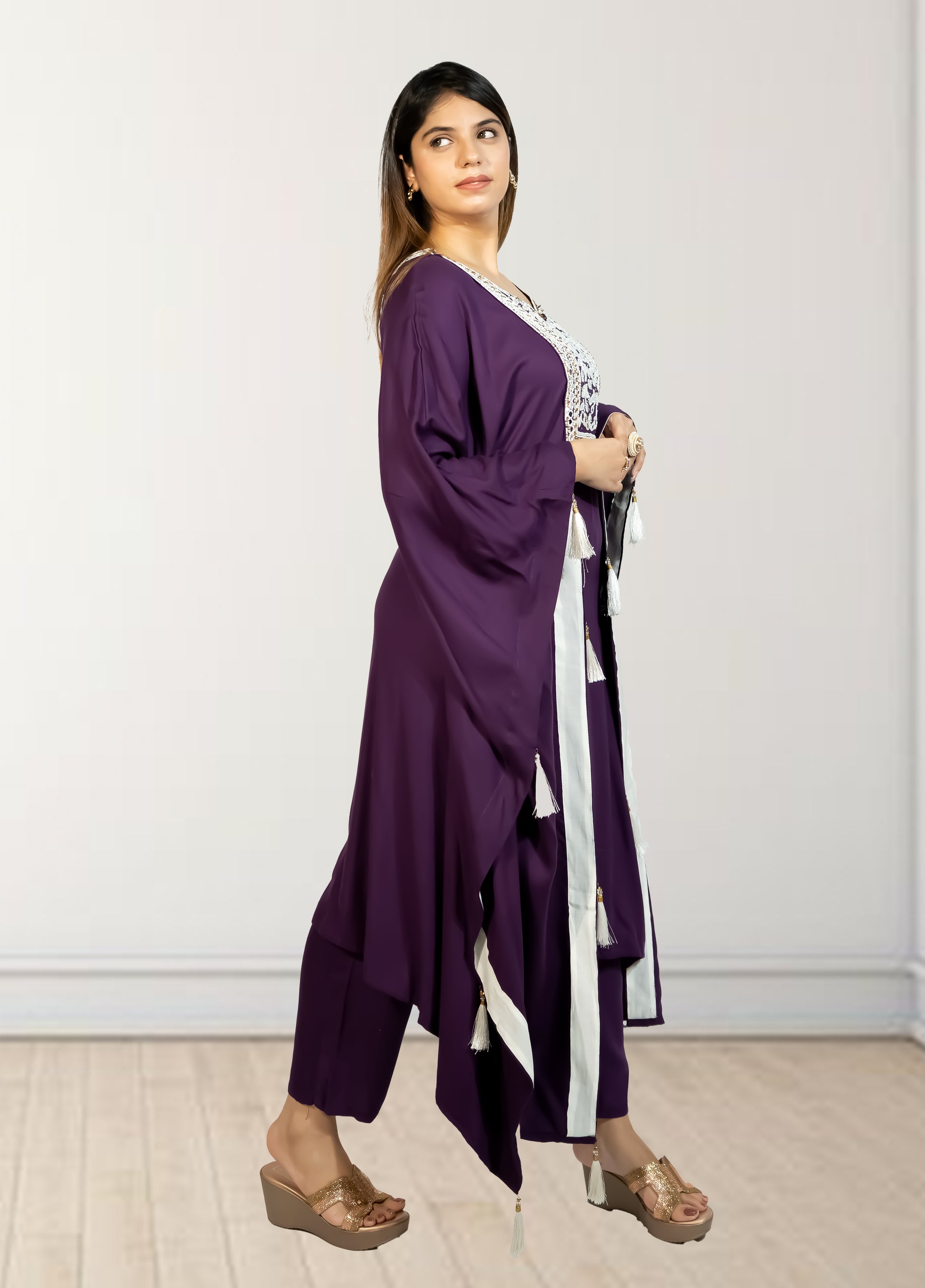 Woman wearing a purple outfit with a white and black scarf against a plain background