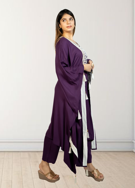 Woman wearing a purple outfit with a white and black scarf against a plain background
