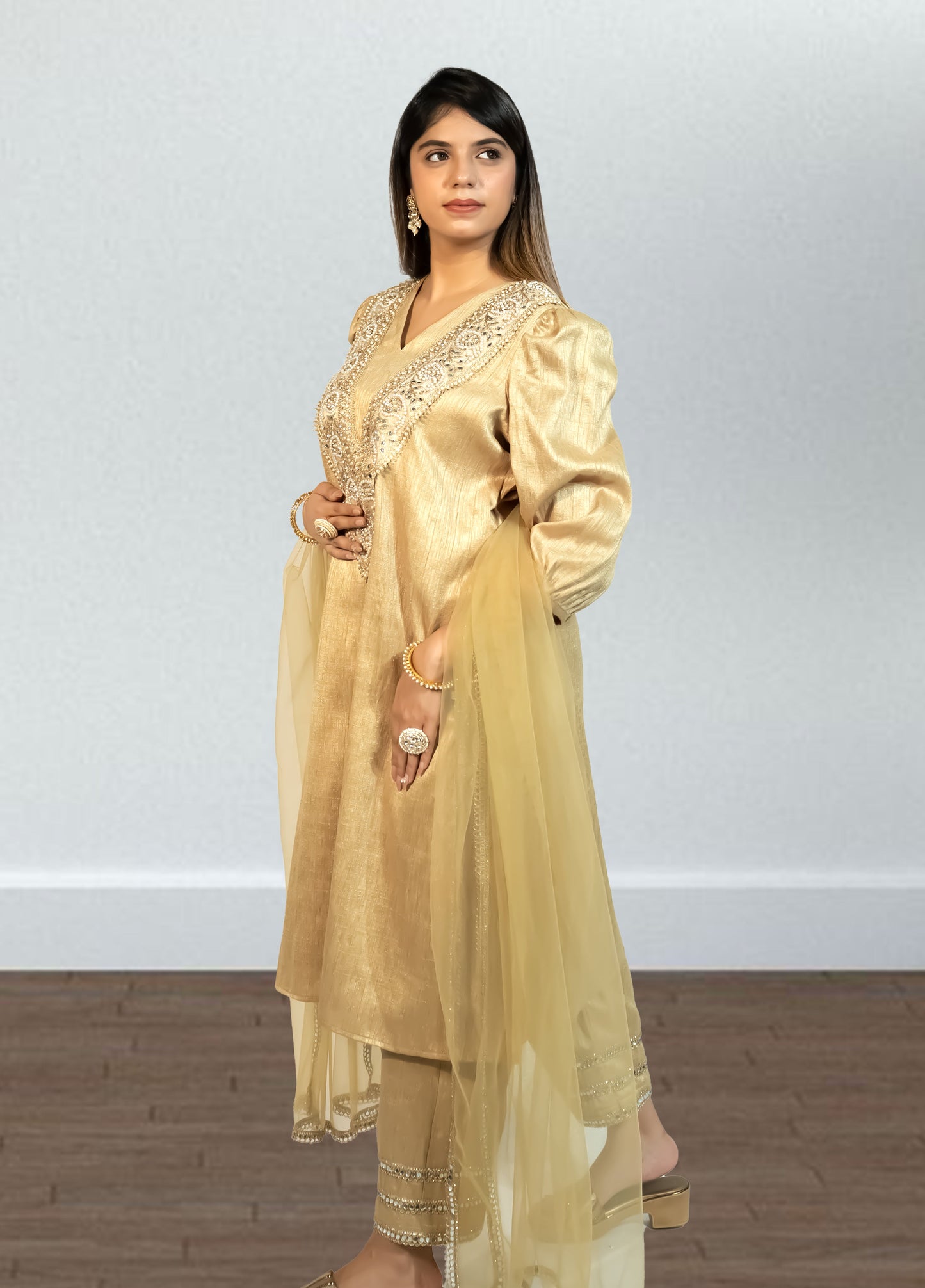 Woman wearing a gold traditional outfit with a plain background