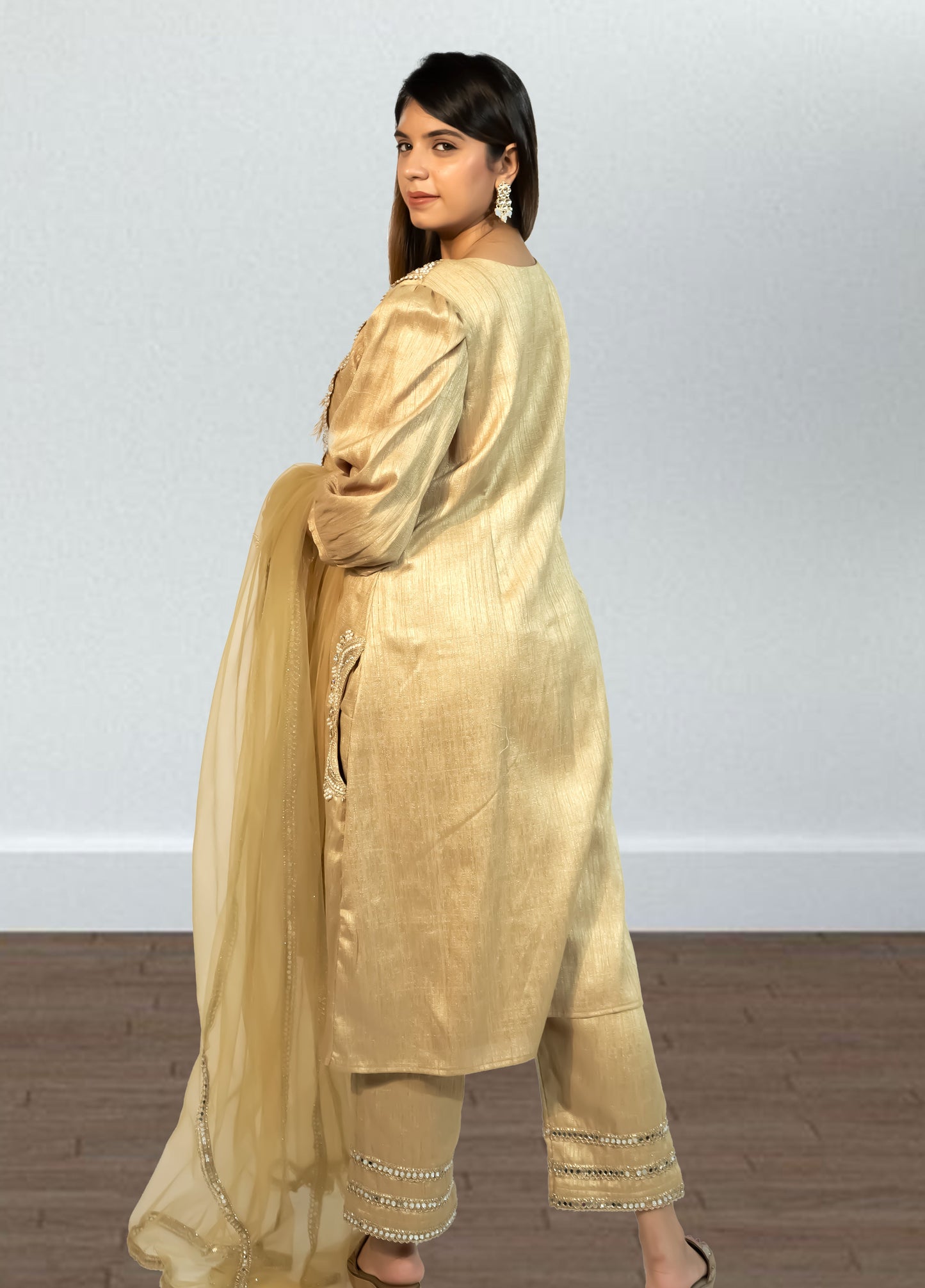 Woman wearing a gold traditional outfit with a plain background