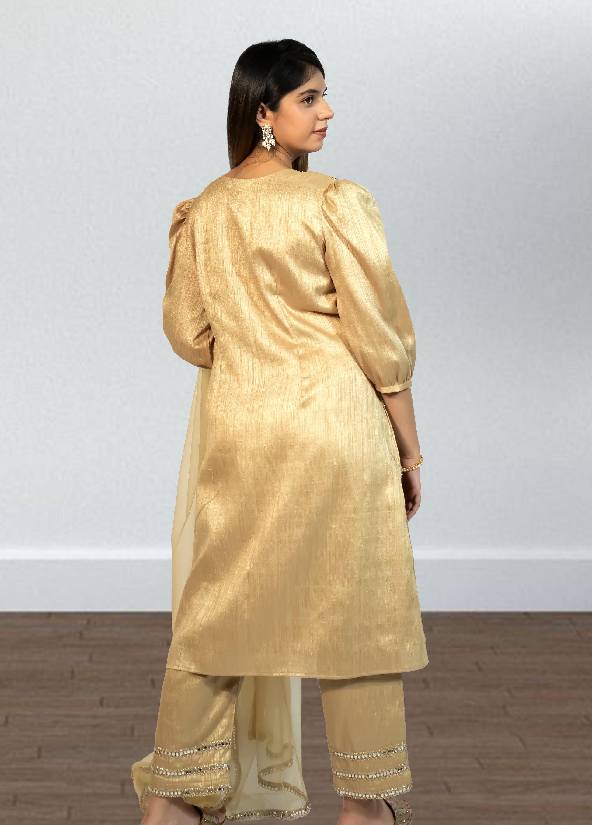 Woman wearing a gold traditional outfit with a plain background