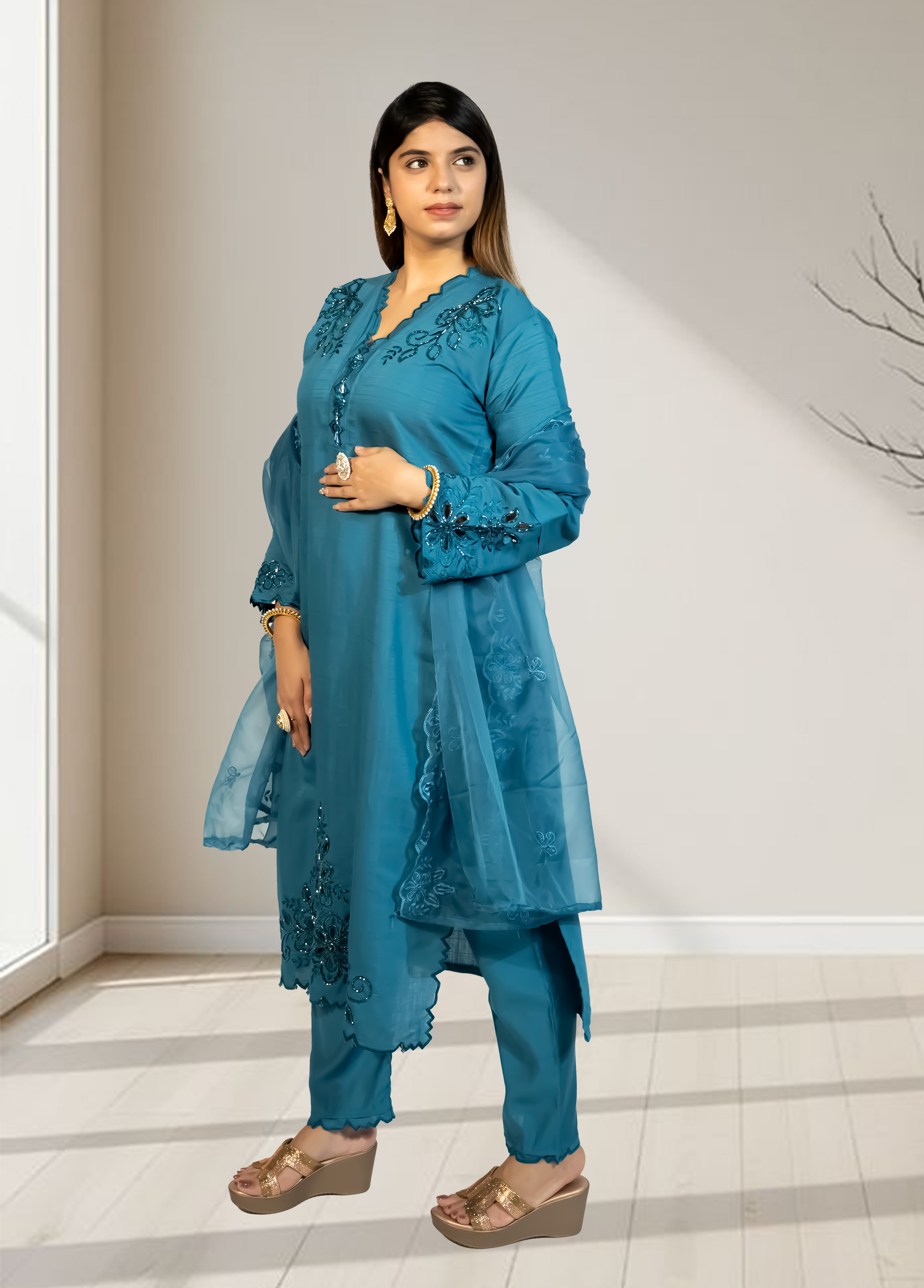 Woman wearing a blue traditional outfit with intricate designs indoors.