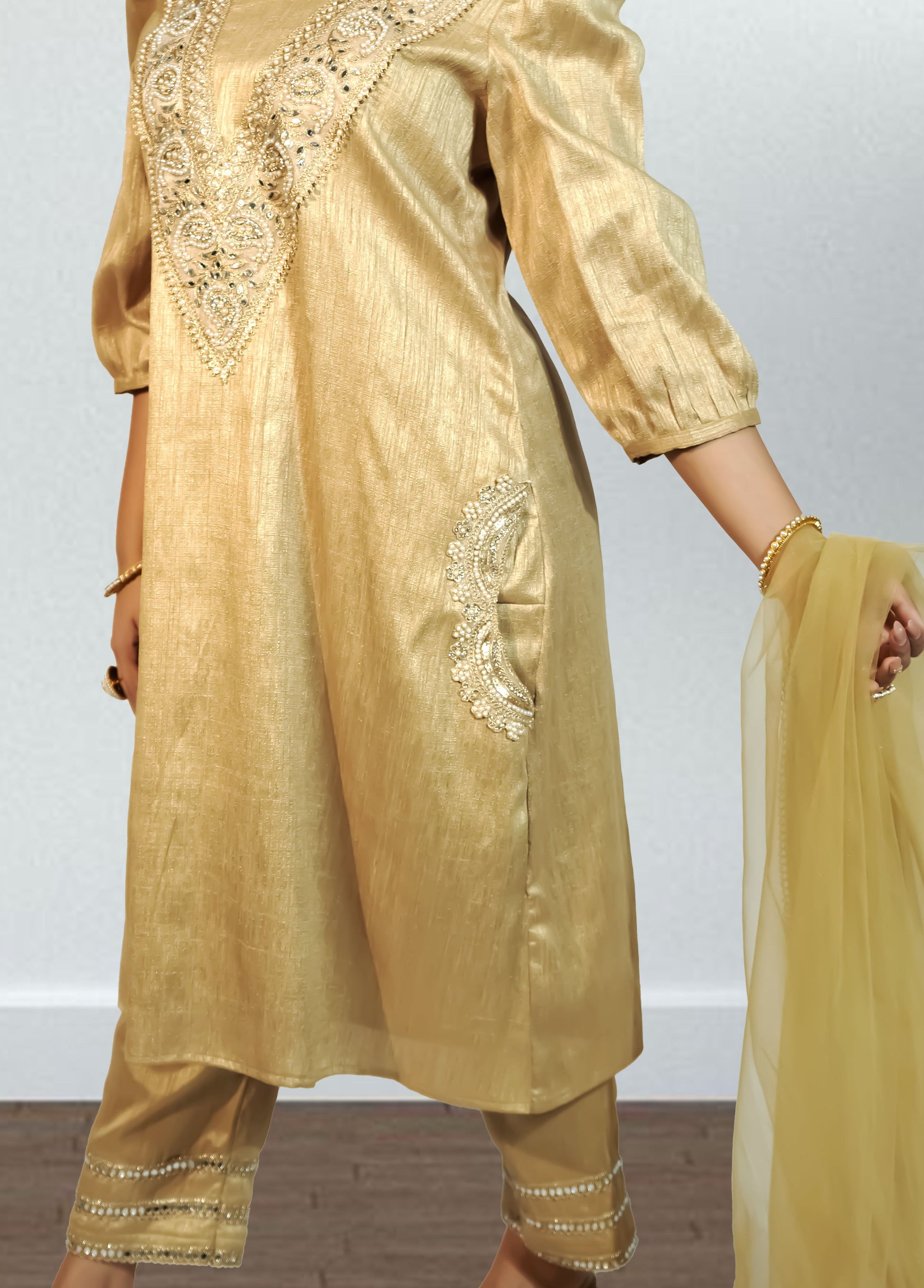 Gold traditional outfit with intricate designs on a plain background