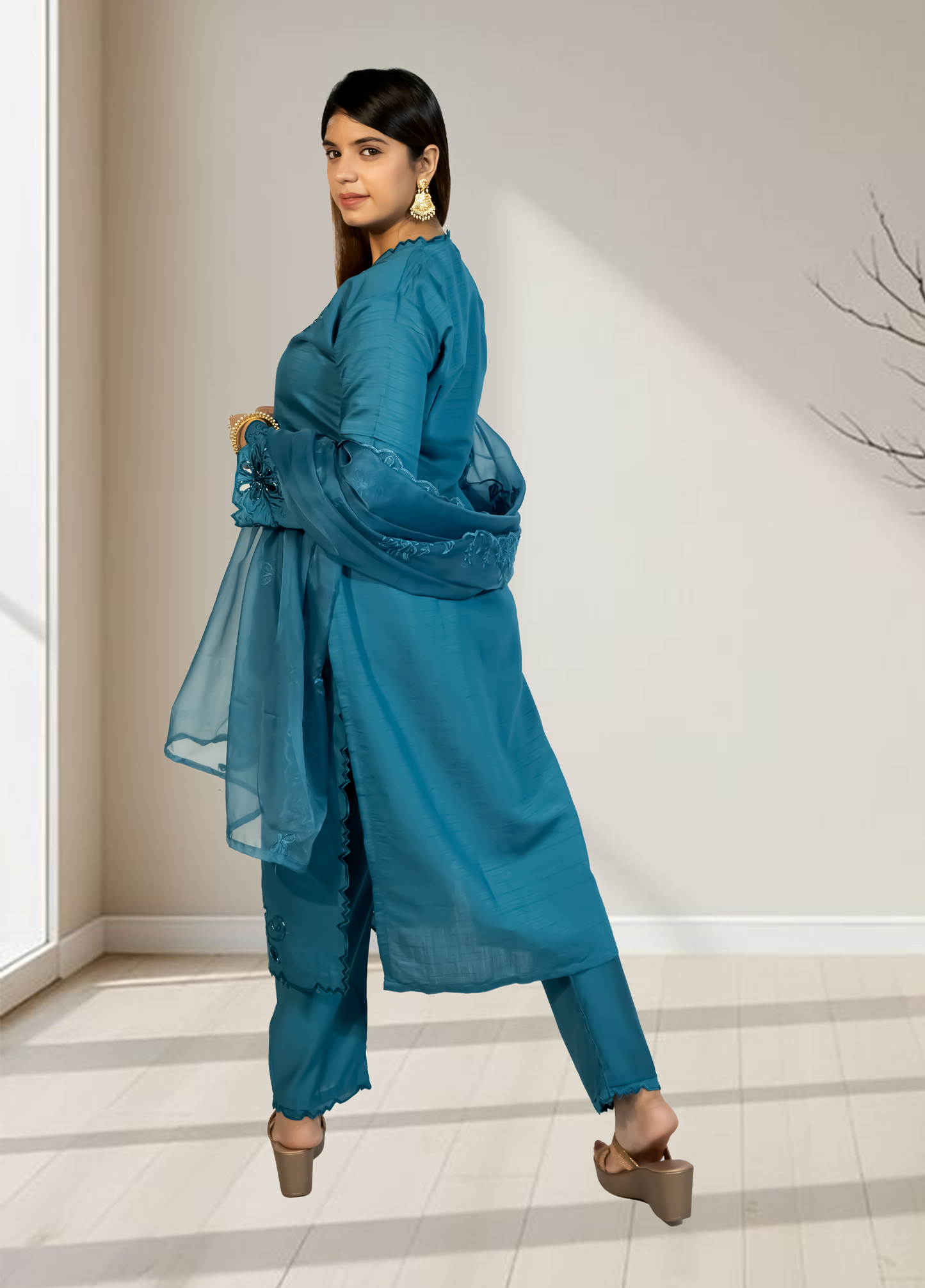Woman wearing a blue traditional outfit in a minimalistic room.