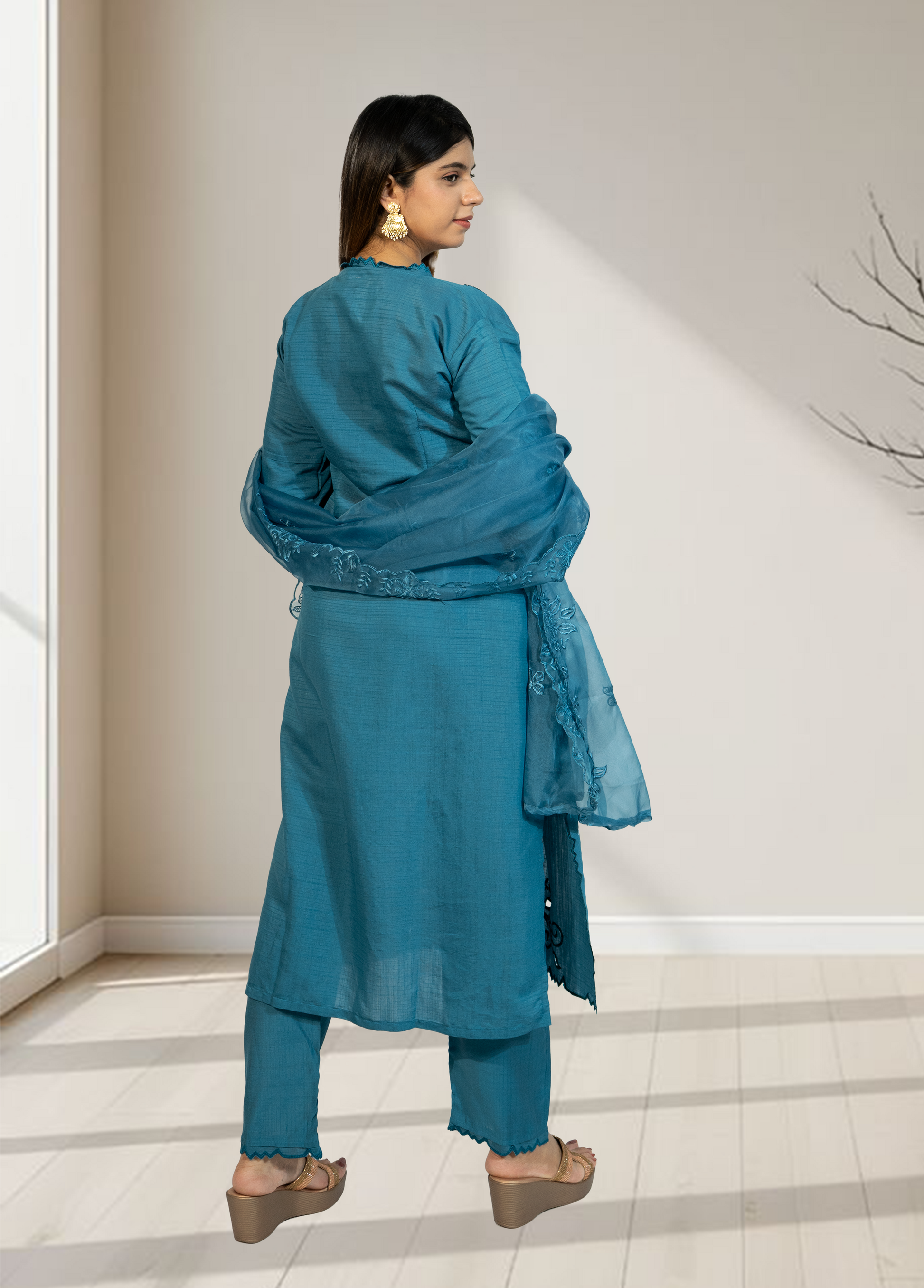 Woman wearing a blue traditional outfit in a minimalistic room.