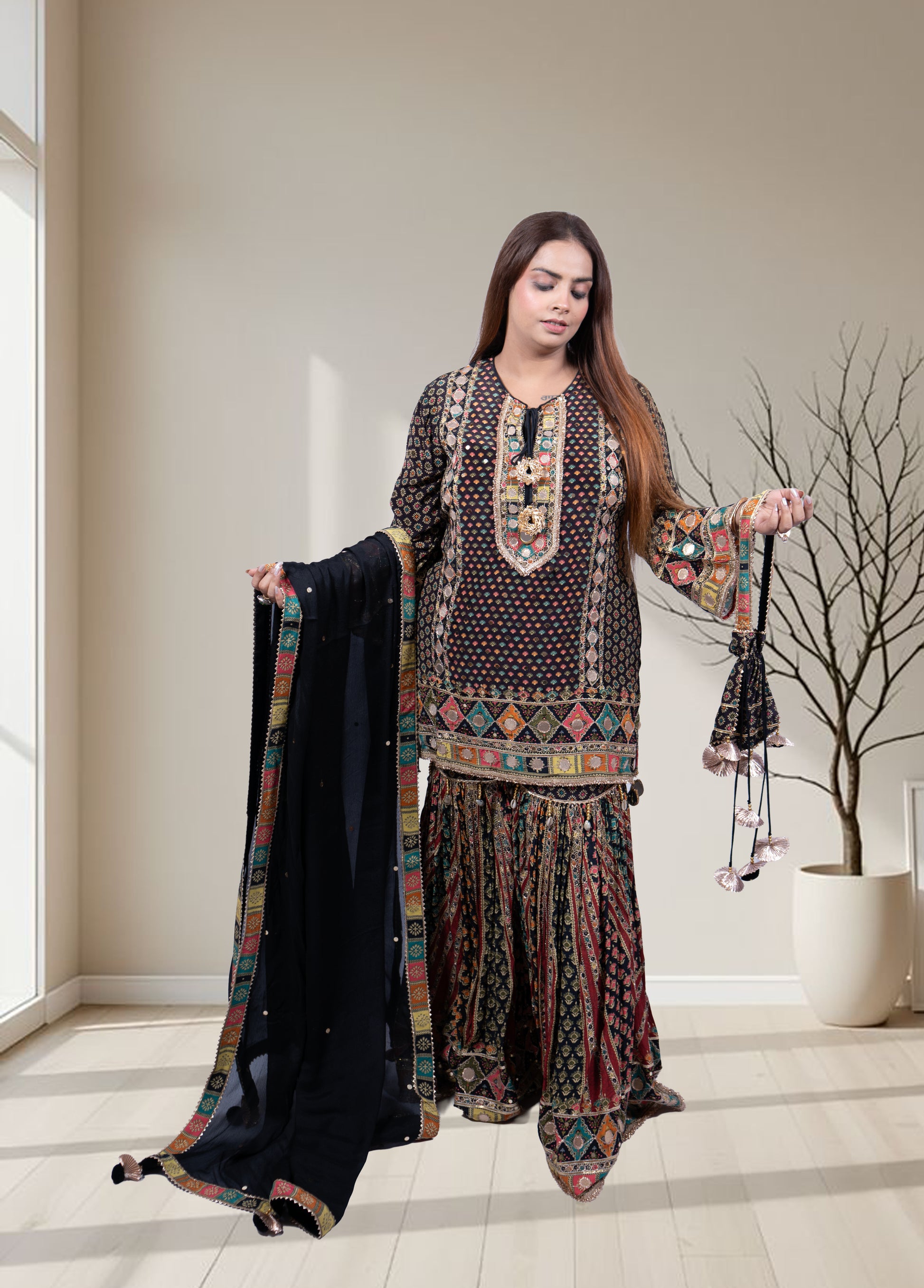 Woman holding a traditional outfit with a black dupatta in a well-lit room.