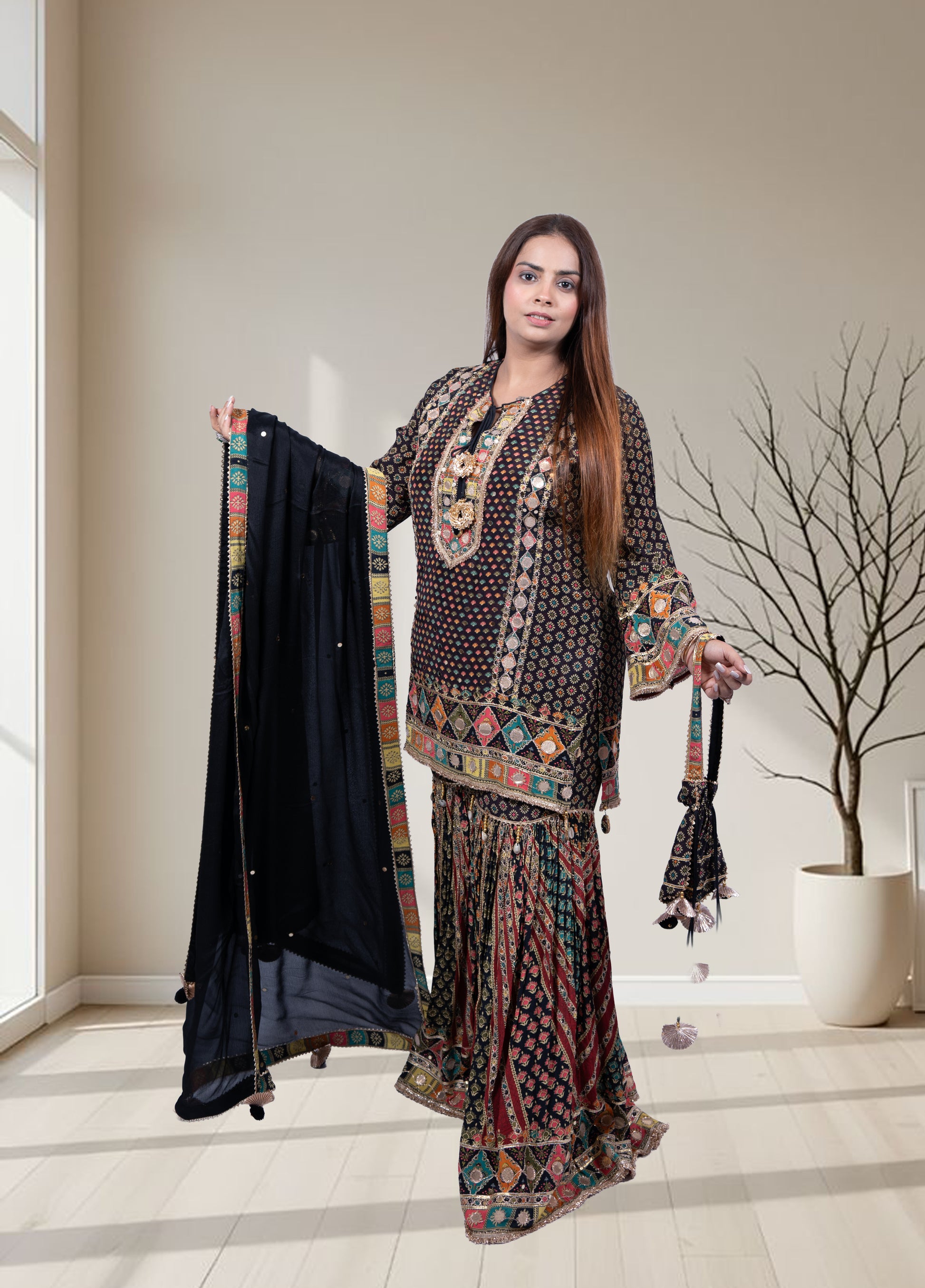 Woman holding a traditional outfit with a decorative shawl in a well-lit room.