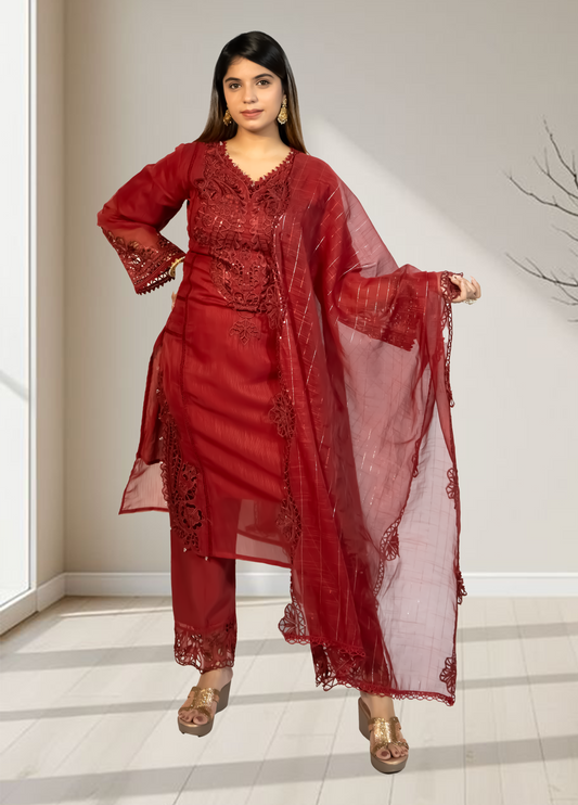 Woman wearing a red traditional outfit with a matching dupatta in a minimal indoor setting.