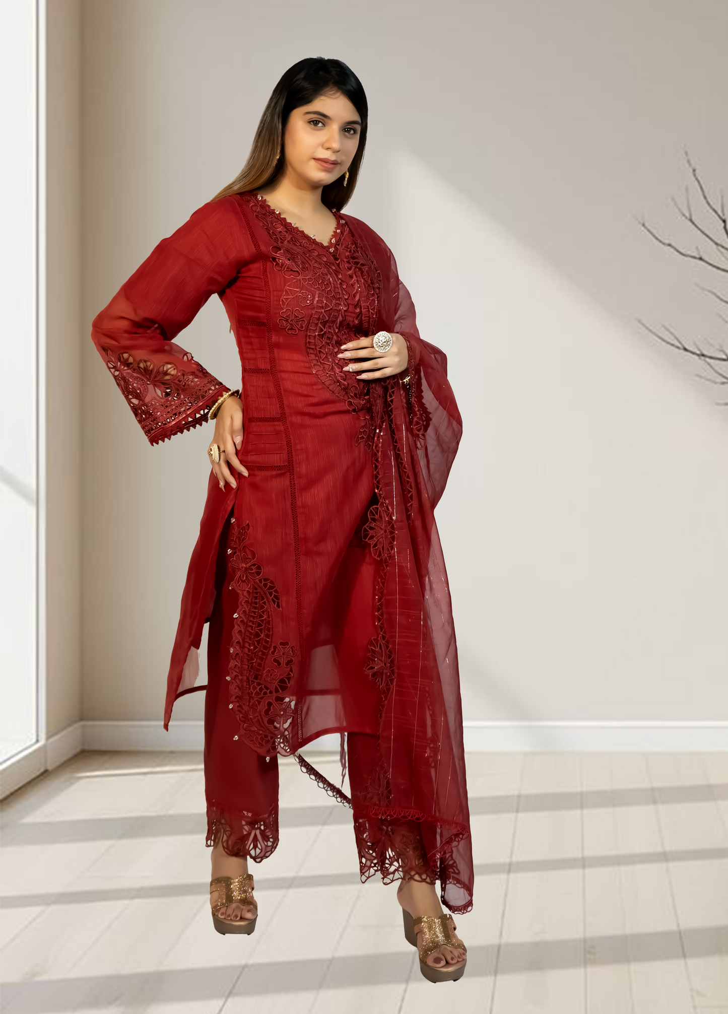 Woman wearing a red traditional outfit with lace details in a minimal indoor setting.