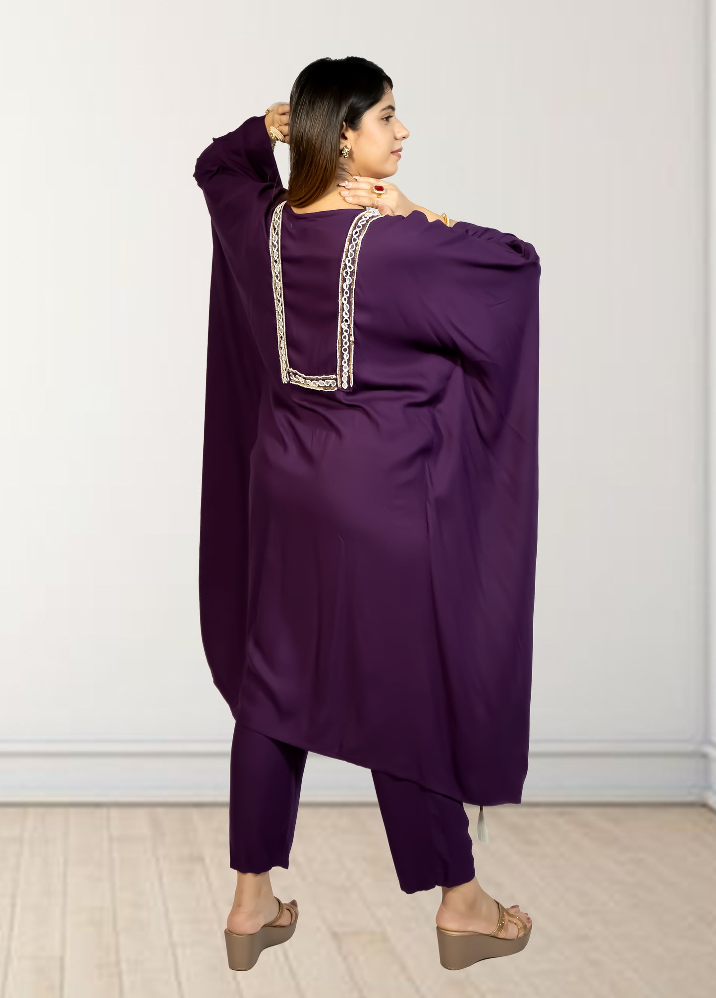 Person wearing a purple outfit with intricate detailing on a white background