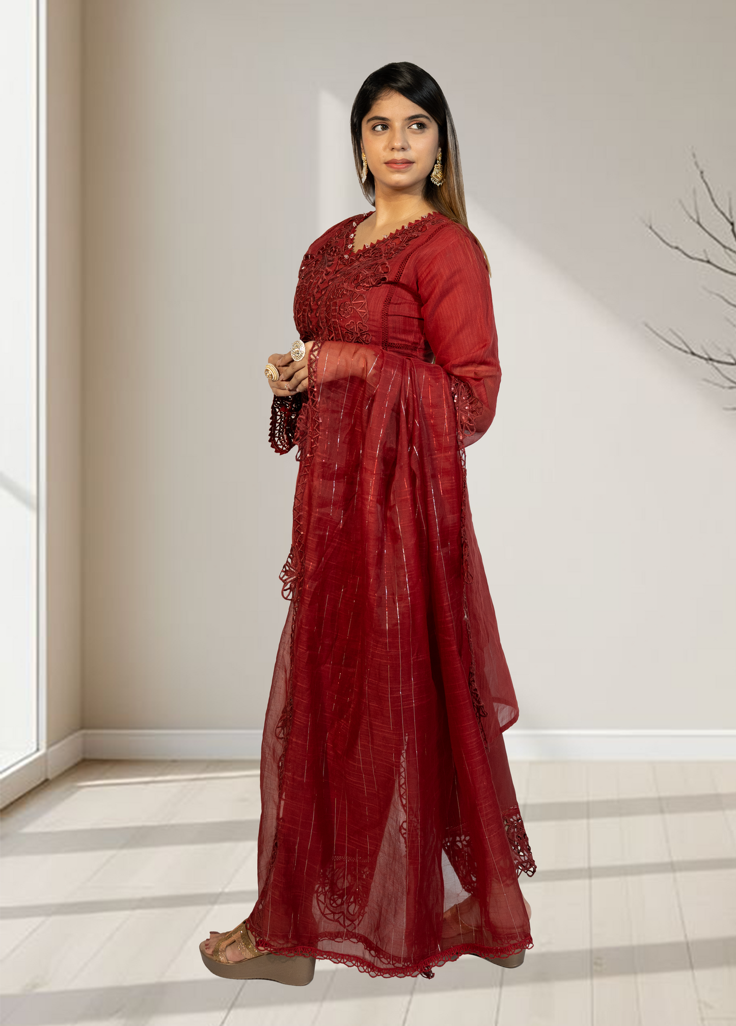 Woman wearing a red traditional outfit in a minimalistic room.