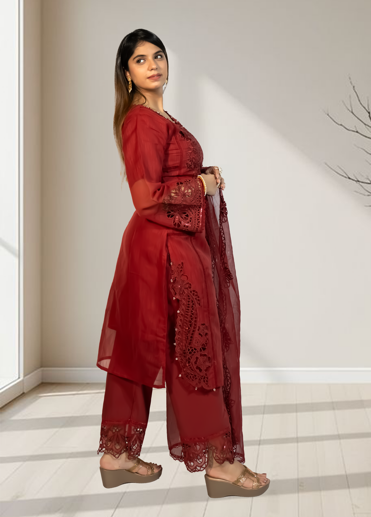 Woman wearing a red embroidered outfit standing in a well-lit room.