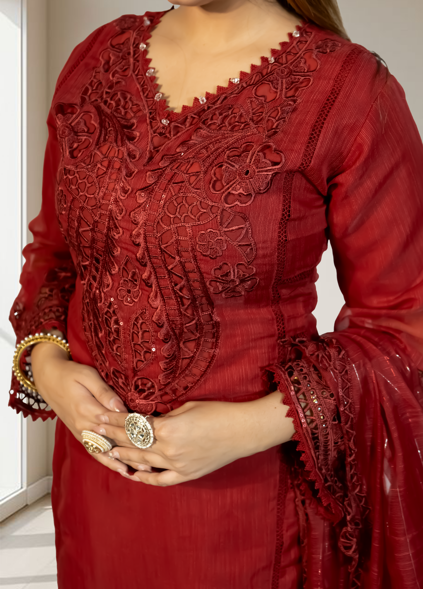 Red embroidered dress with intricate patterns worn by a person indoors.