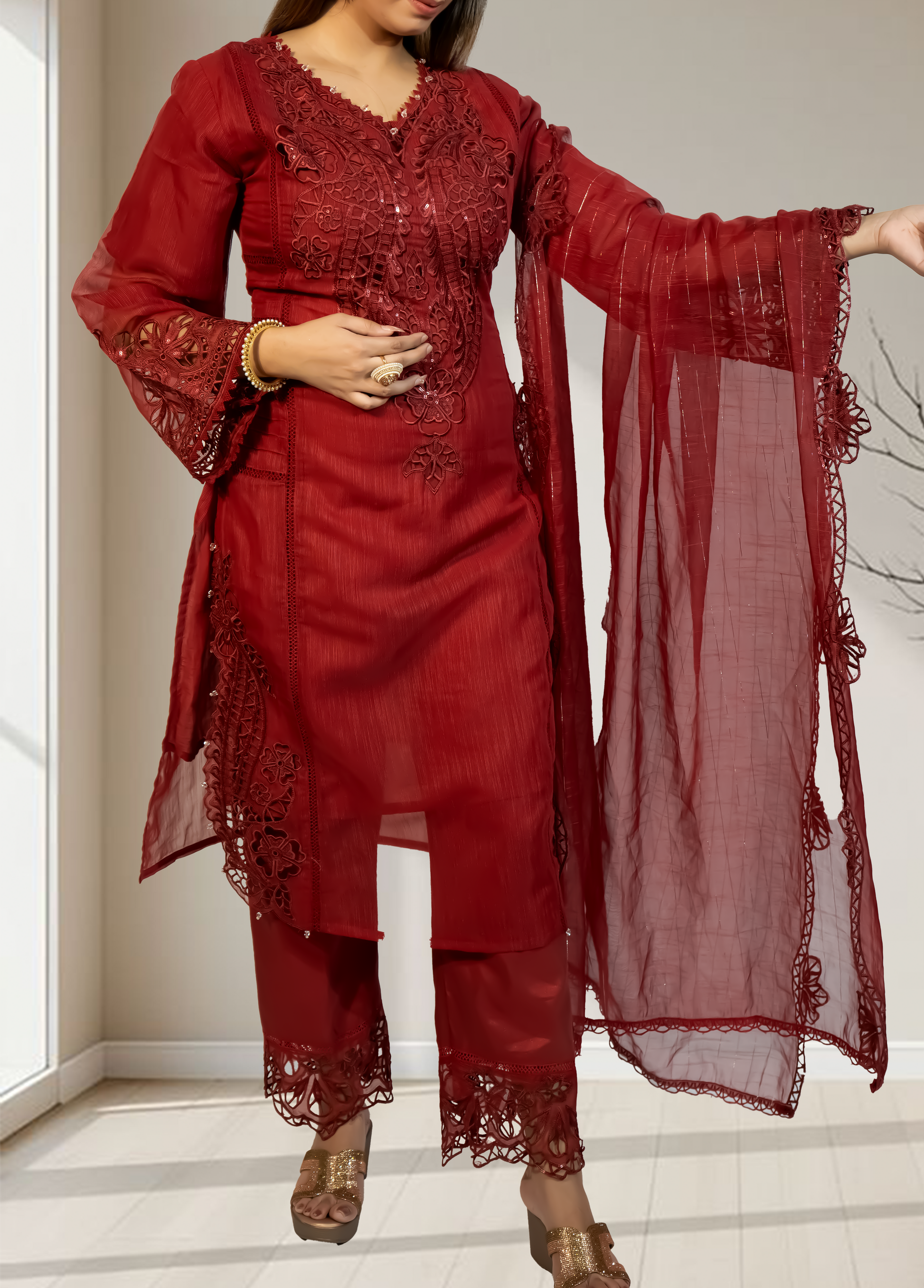 Red embroidered traditional outfit with a matching dupatta held by a person indoors.