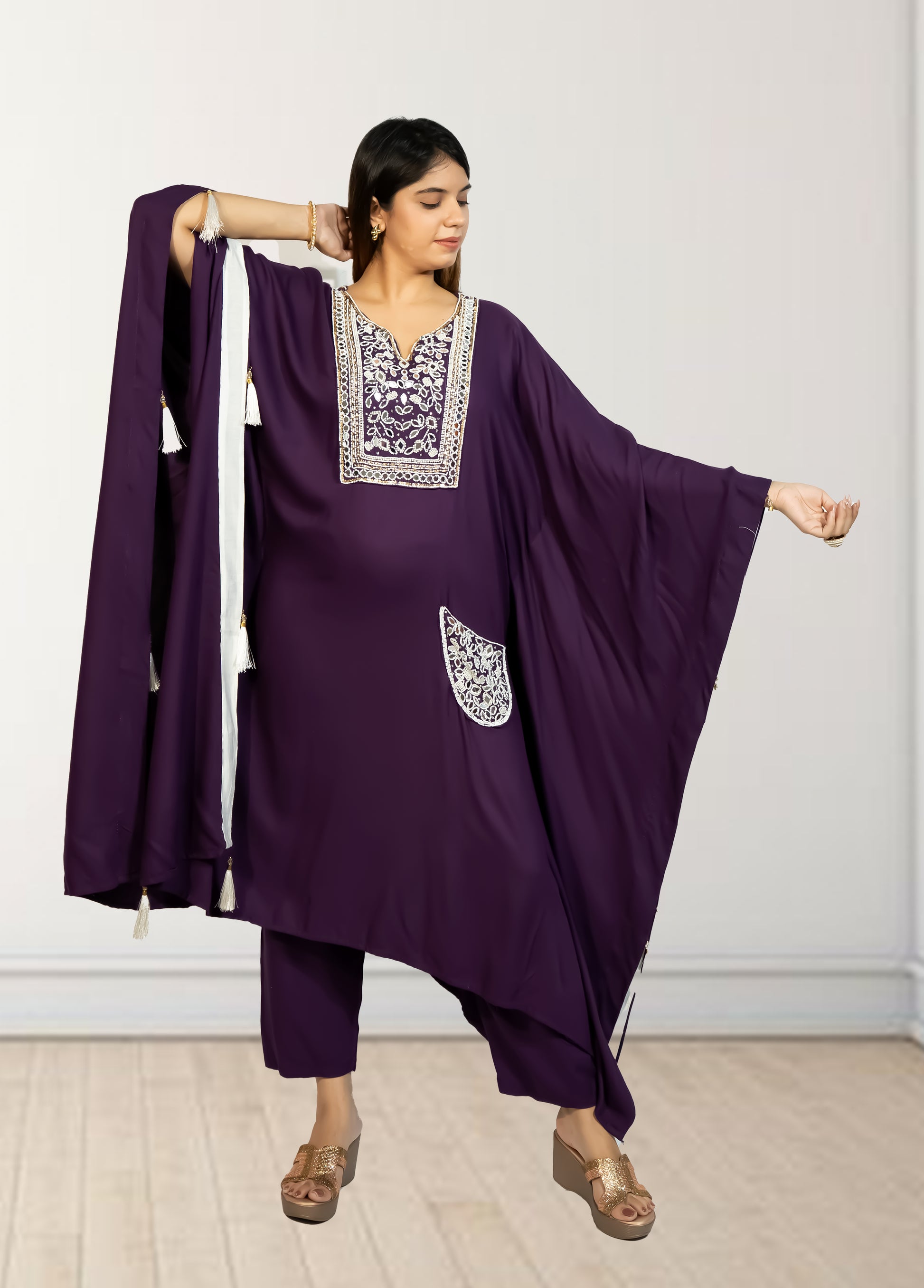 Woman wearing a purple traditional outfit with white embroidery against a plain background