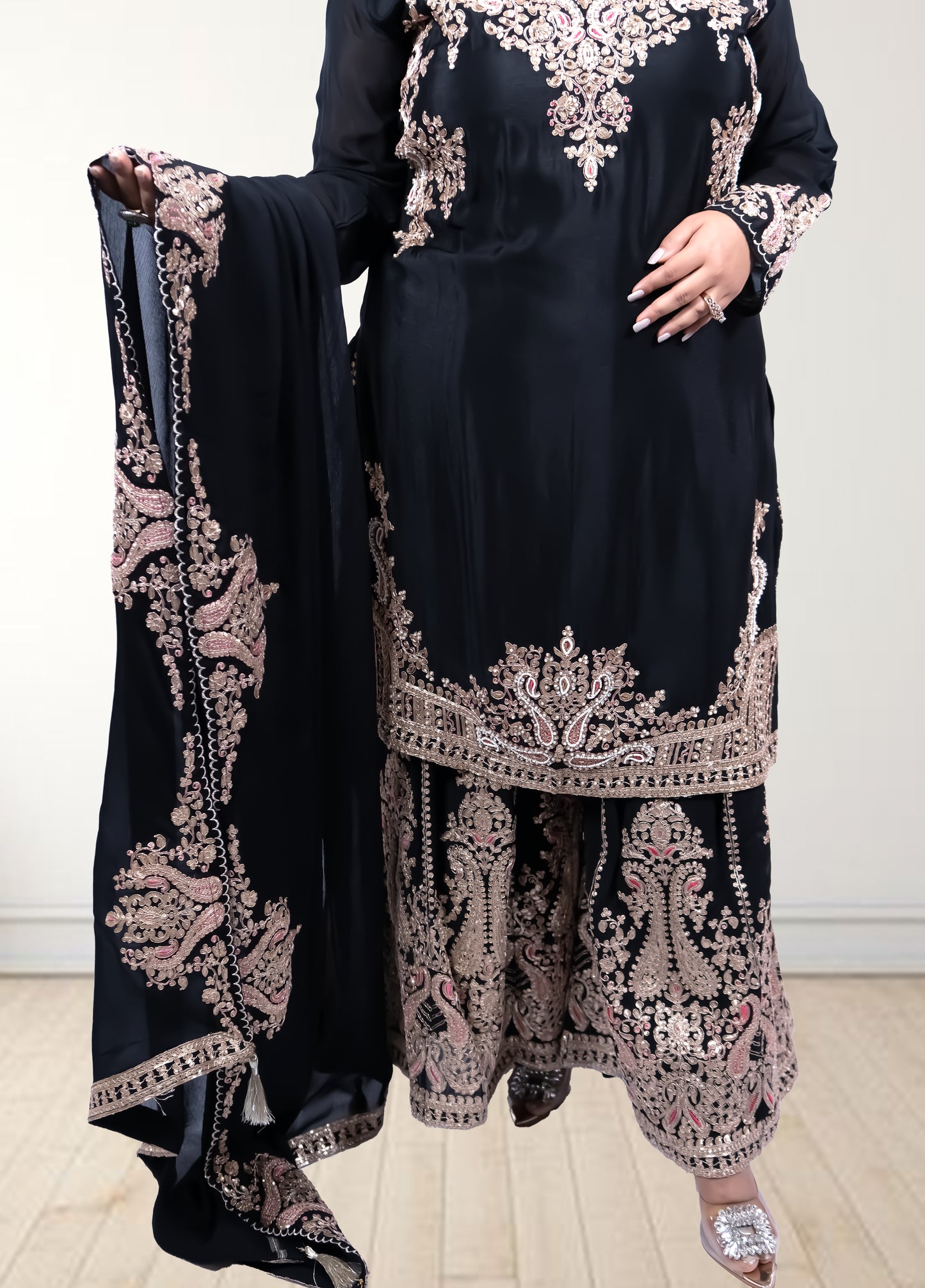 Black traditional outfit with intricate pink embroidery on a white background