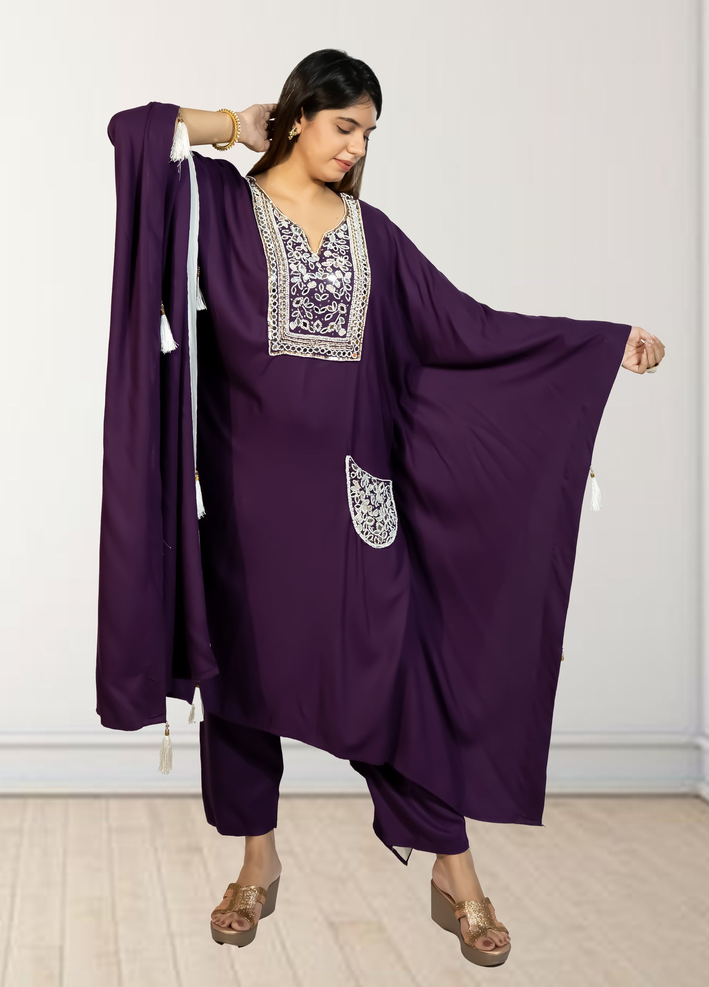Woman wearing a purple traditional outfit with white embroidery against a white background