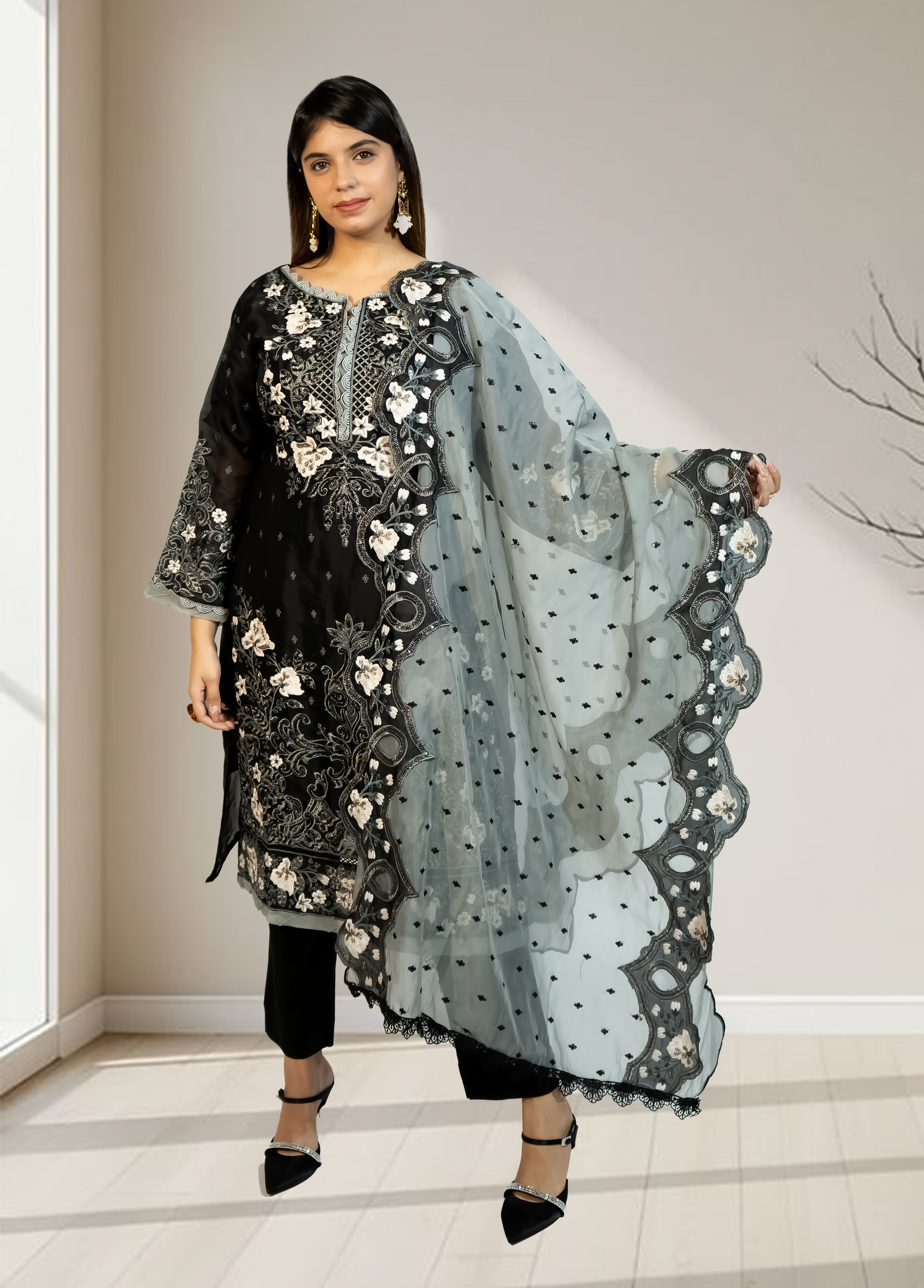 Woman holding a black and white embroidered dupatta in a neutral setting