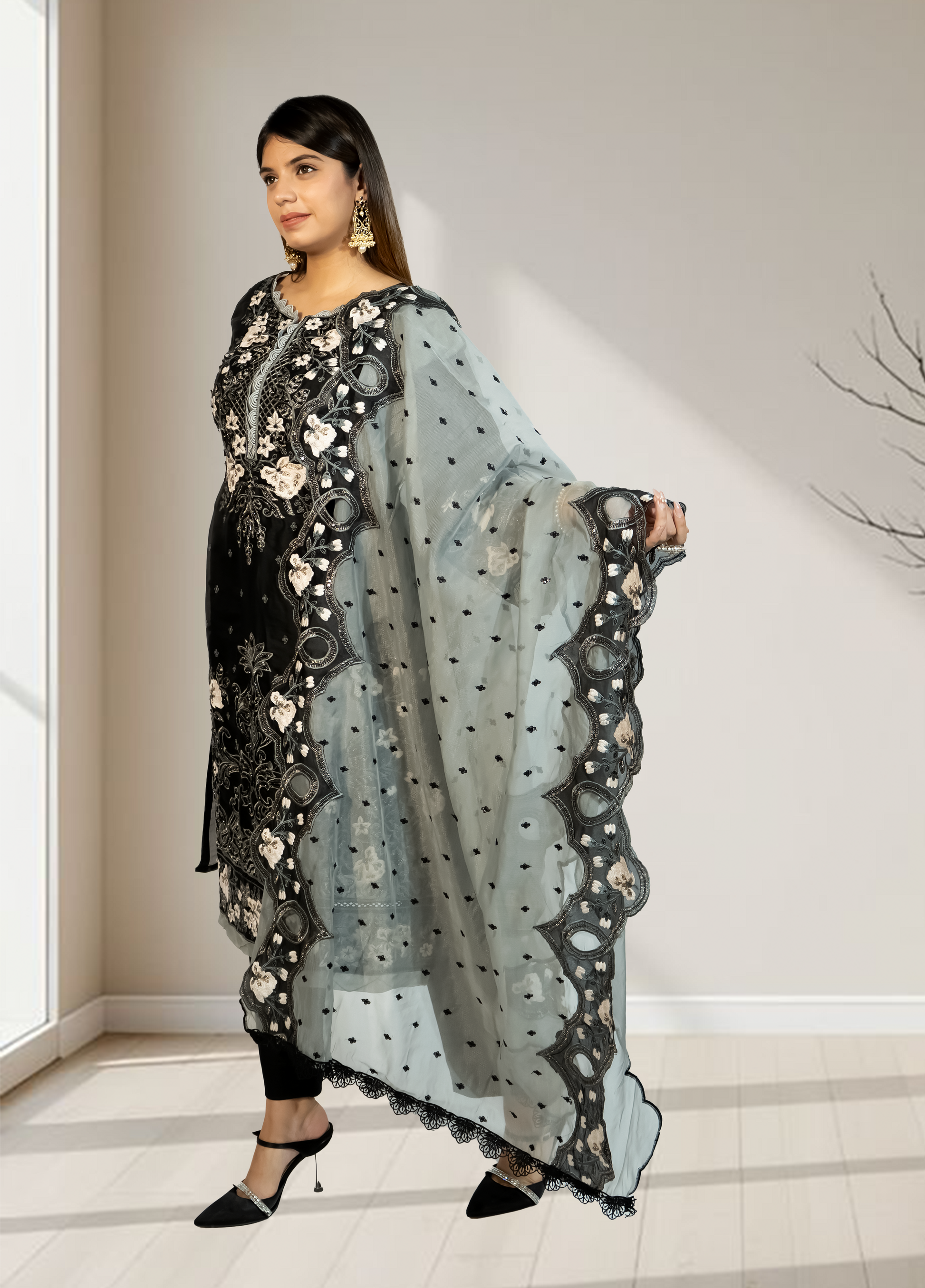 Woman holding a light blue dupatta with floral patterns in a minimal indoor setting